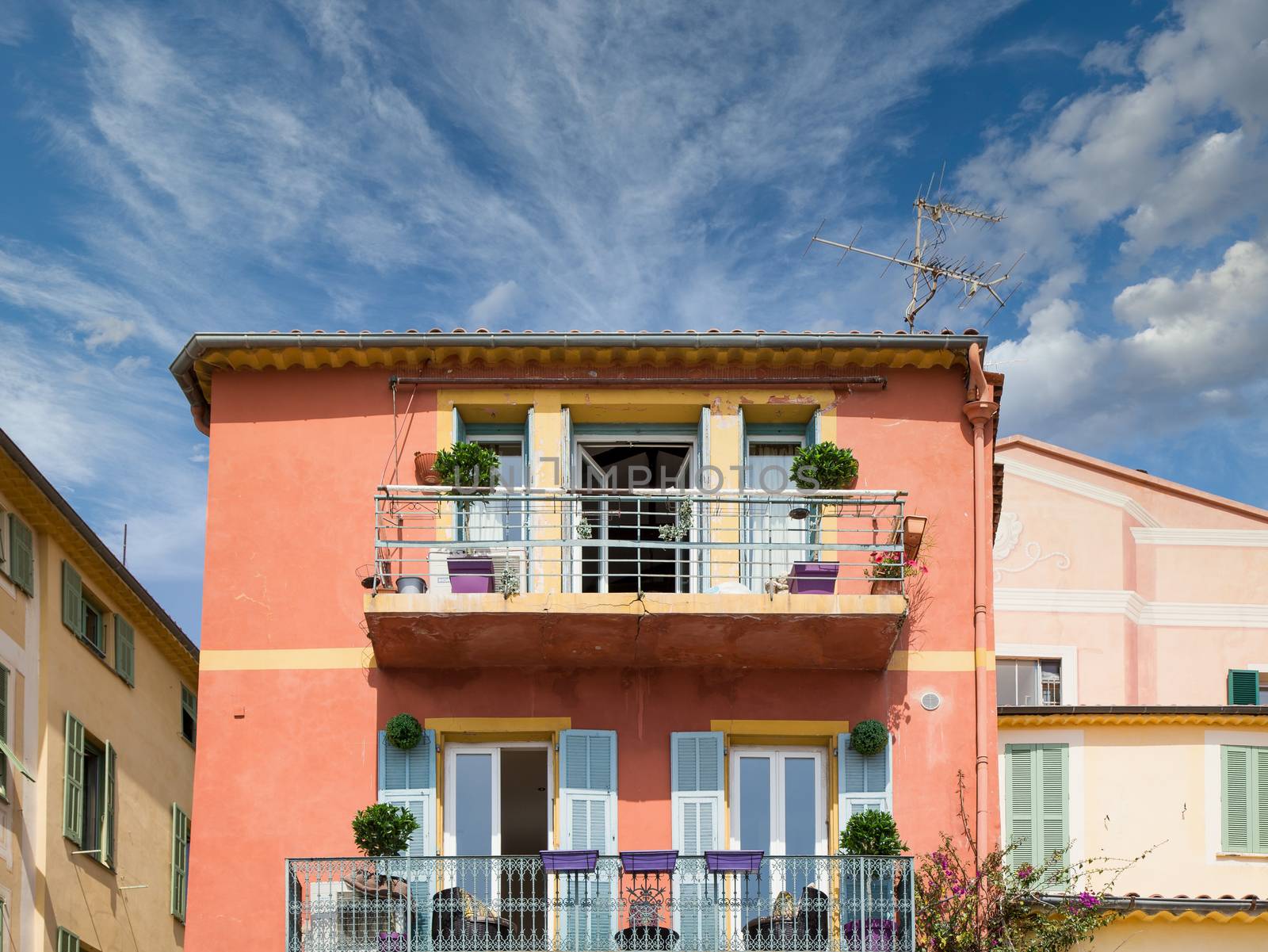 An orange stucco building with blue shutters and colorful planters