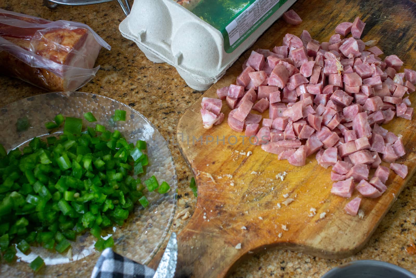 Preparation of a Brazilian meal, with sliced pork sausage, parsley, eggs and bacon