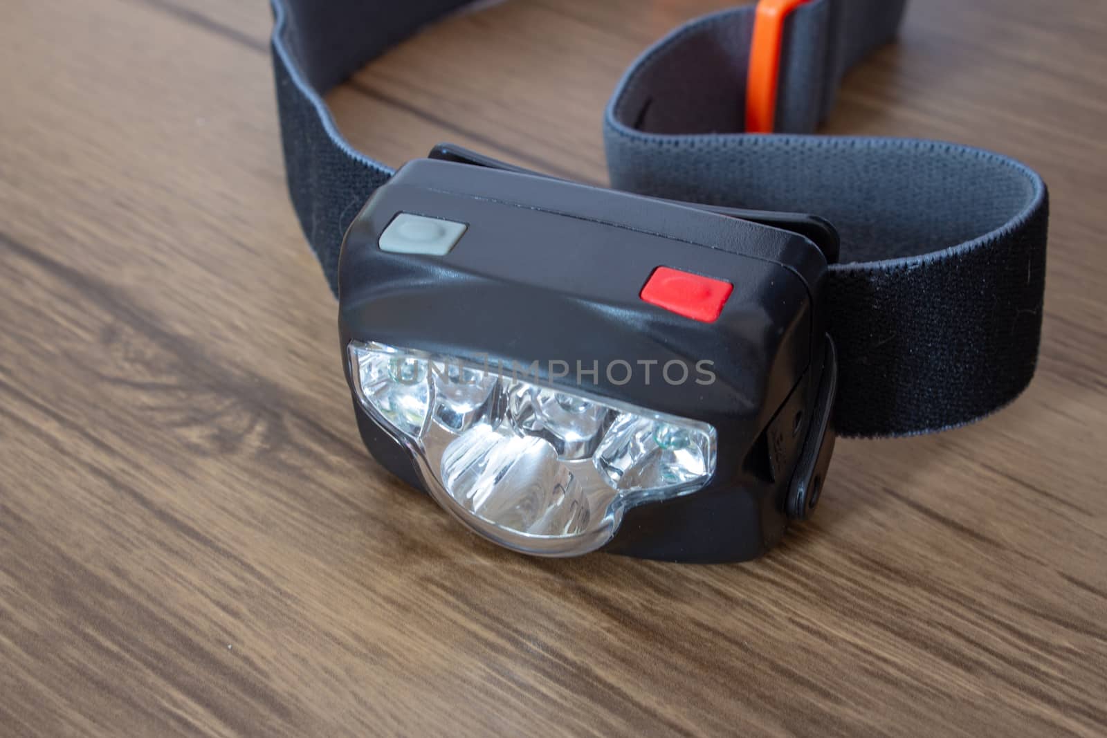 Black led headlamp turned off on a wooden table showing the elastic strap