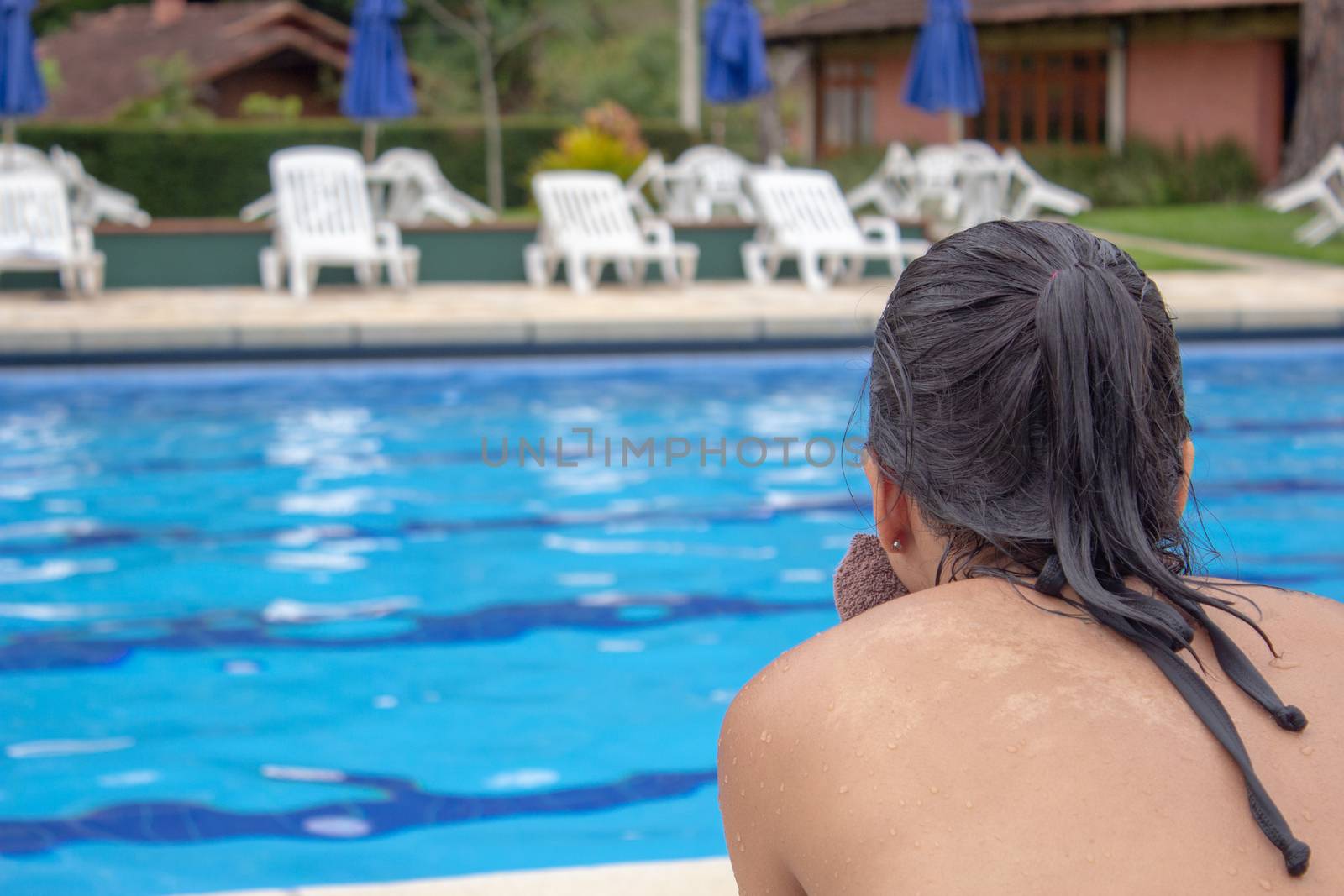 Woman after getting out the pool, gazing at the blue water