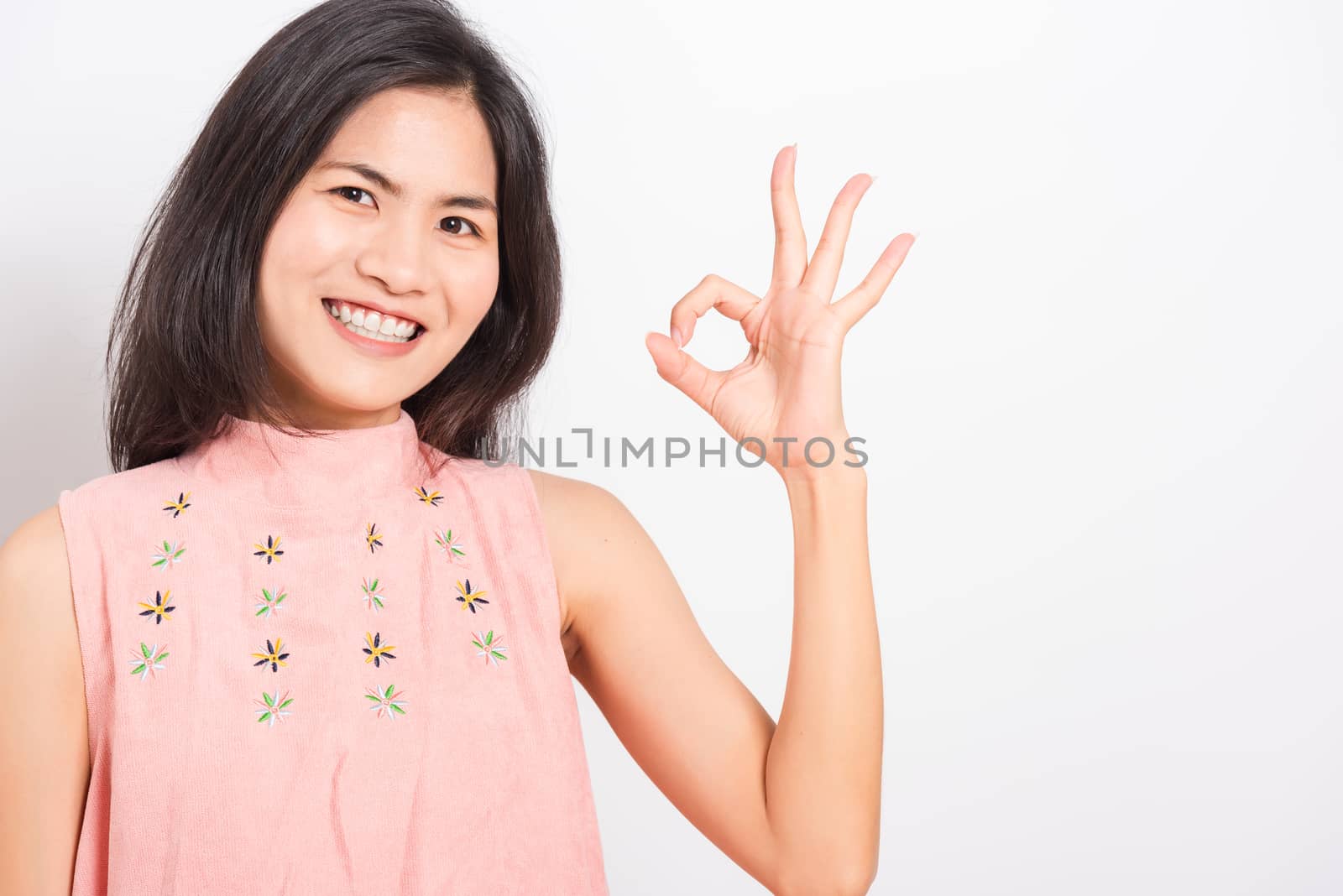 Portrait Asian beautiful young woman standing, She made finger OK symbol sign to agree and looking at camera, shoot photo in studio on white background, There was copy space