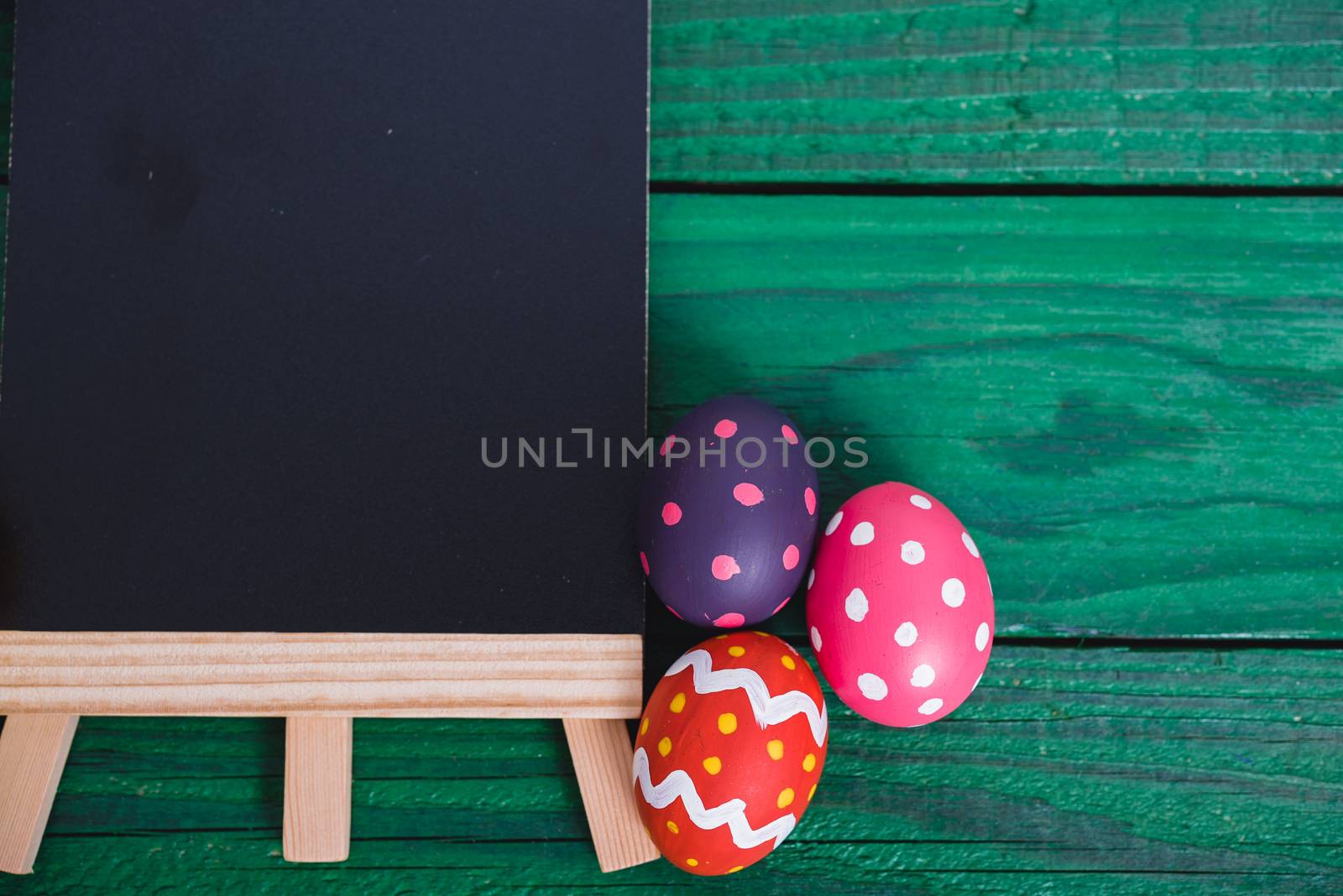 Easter eggs top view on green wooden background and have board work space board for use