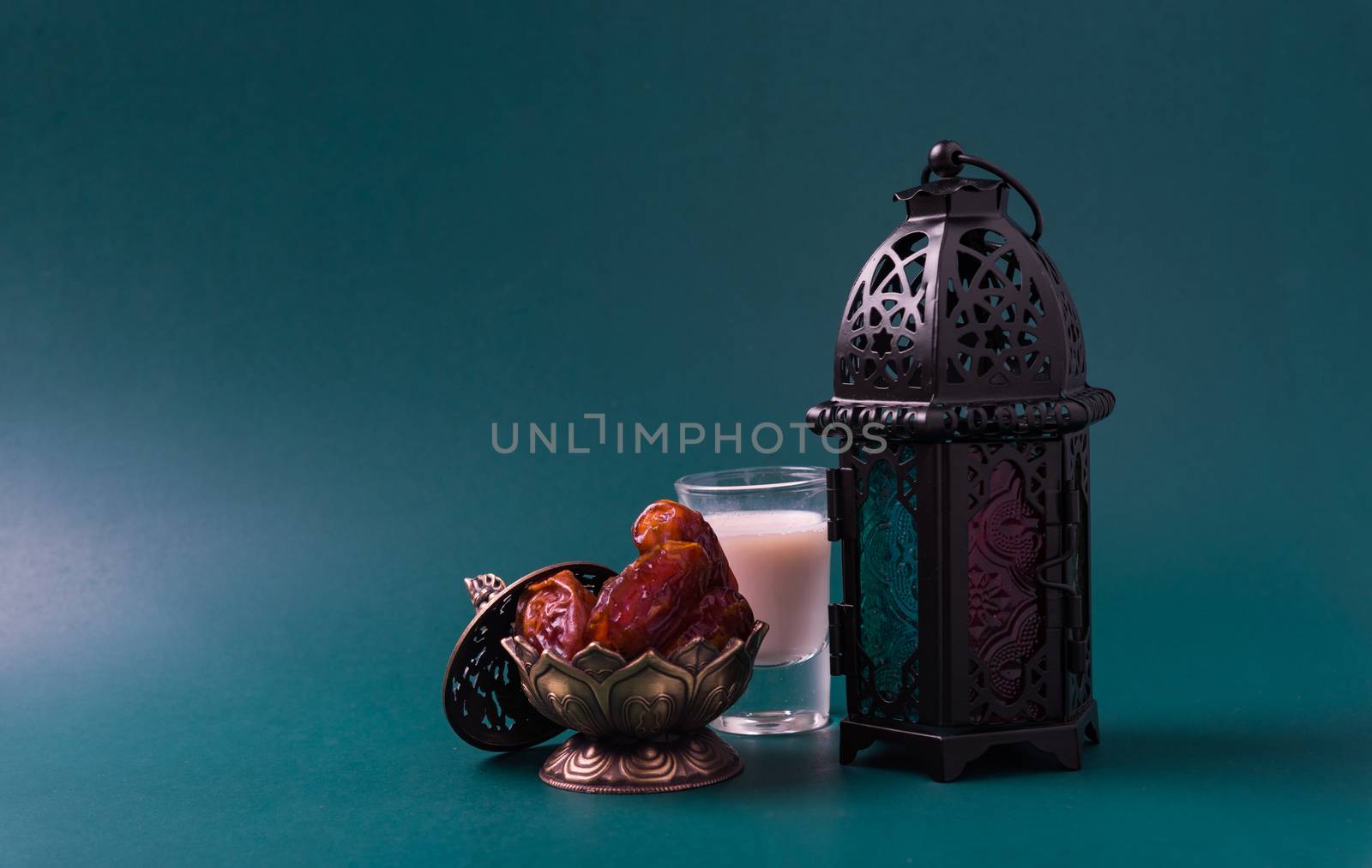 Ramadan Kareem fasting Food Concept, Bronze plate dates, milk, and lantern Aladdin lamp decoration, eid Arabian Muslim religious festival on a dark green background with copy space for text