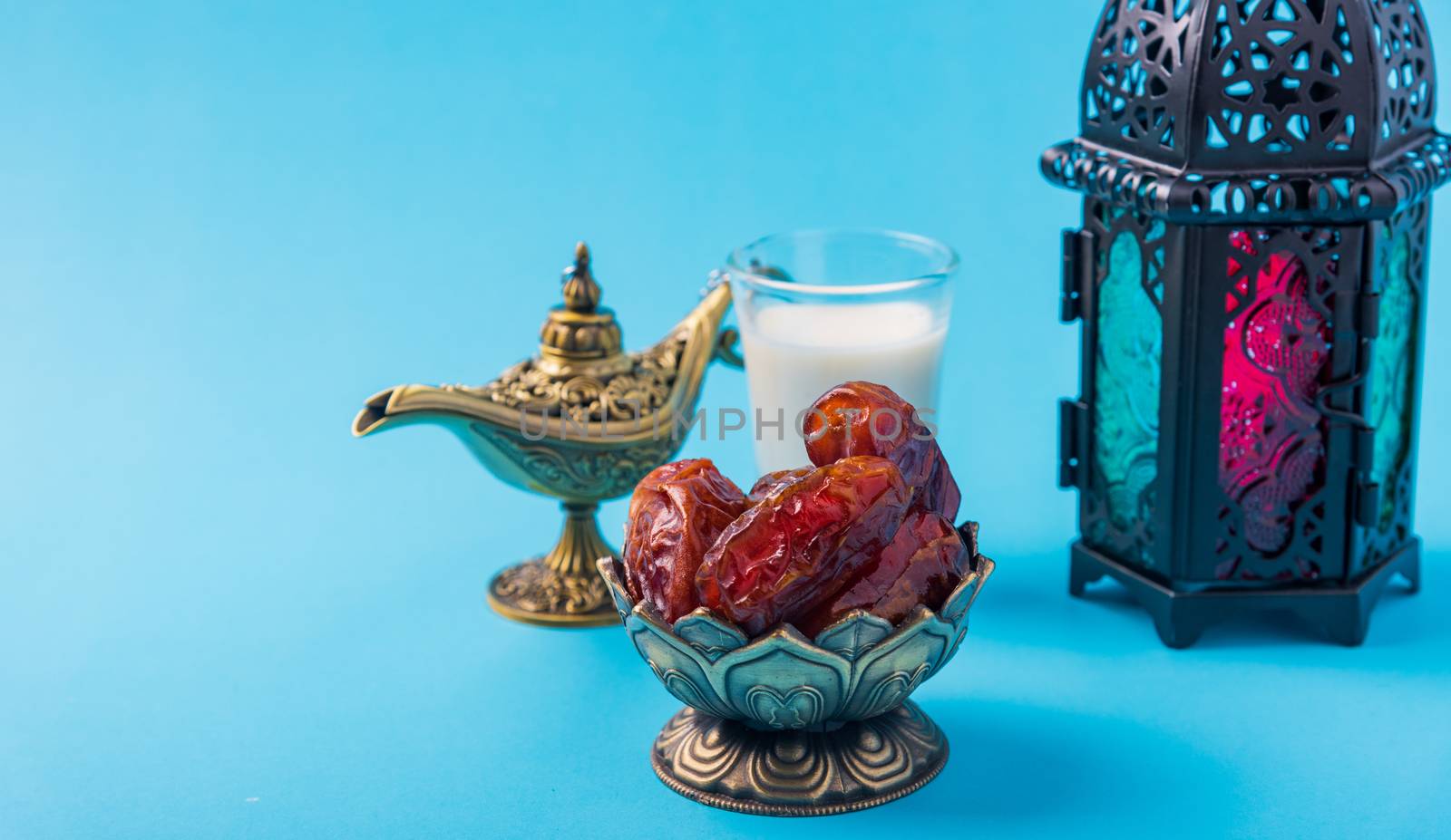 Ramadan Kareem fasting Food Concept, Bronze plate dates, milk, and lantern Aladdin lamp decoration, eid Arabian Muslim religious festival on a blue background with copy space for text