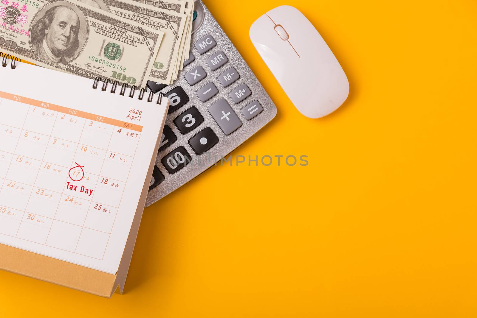 April of the year is Tax Day, Top view flat lay closeup calculator, laptop computer, calendar, and Dollar money, on yellow background business finance budget concept with copy space for text