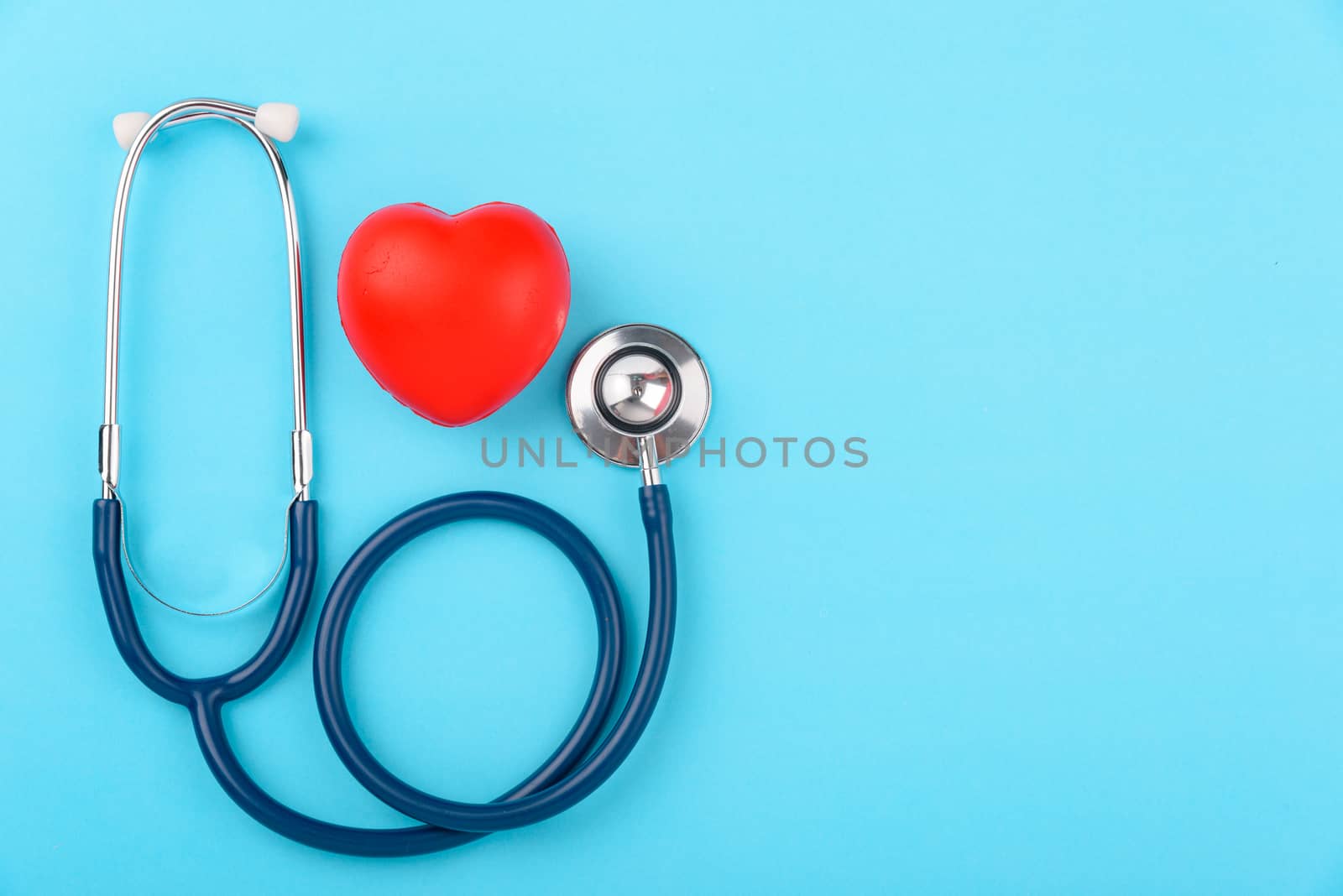 Doctor's Day concept, flat lay top view, stethoscope with red hearts diagnosis of heart disease on blue background with copy space for text