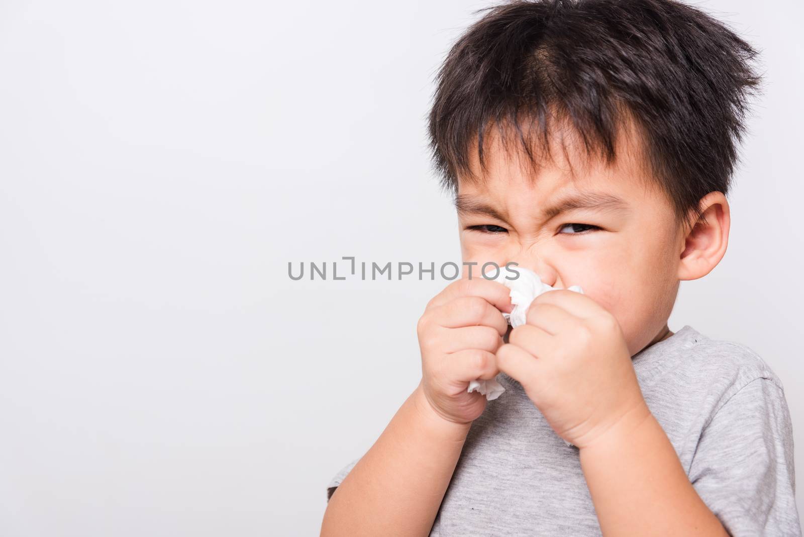 Closeup Asian face, Little children boy cleaning nose with tissue on white background with copy space, health medical care