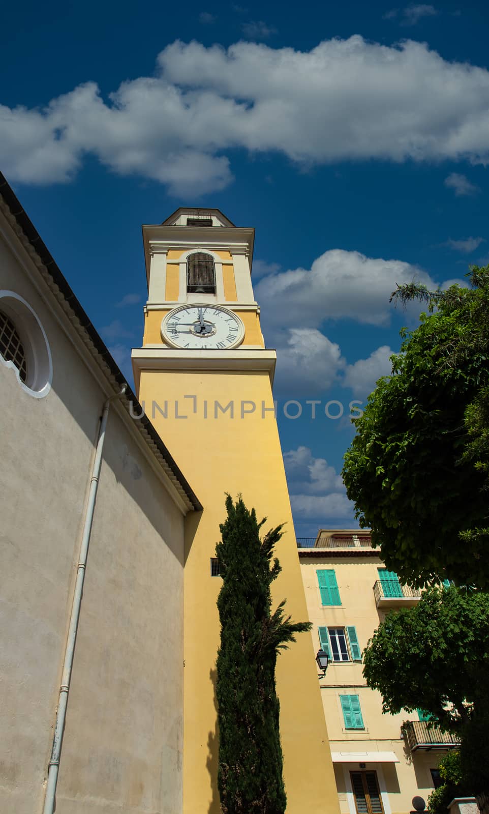 Yellow clock tower in Villefranche, France under clear blue skies