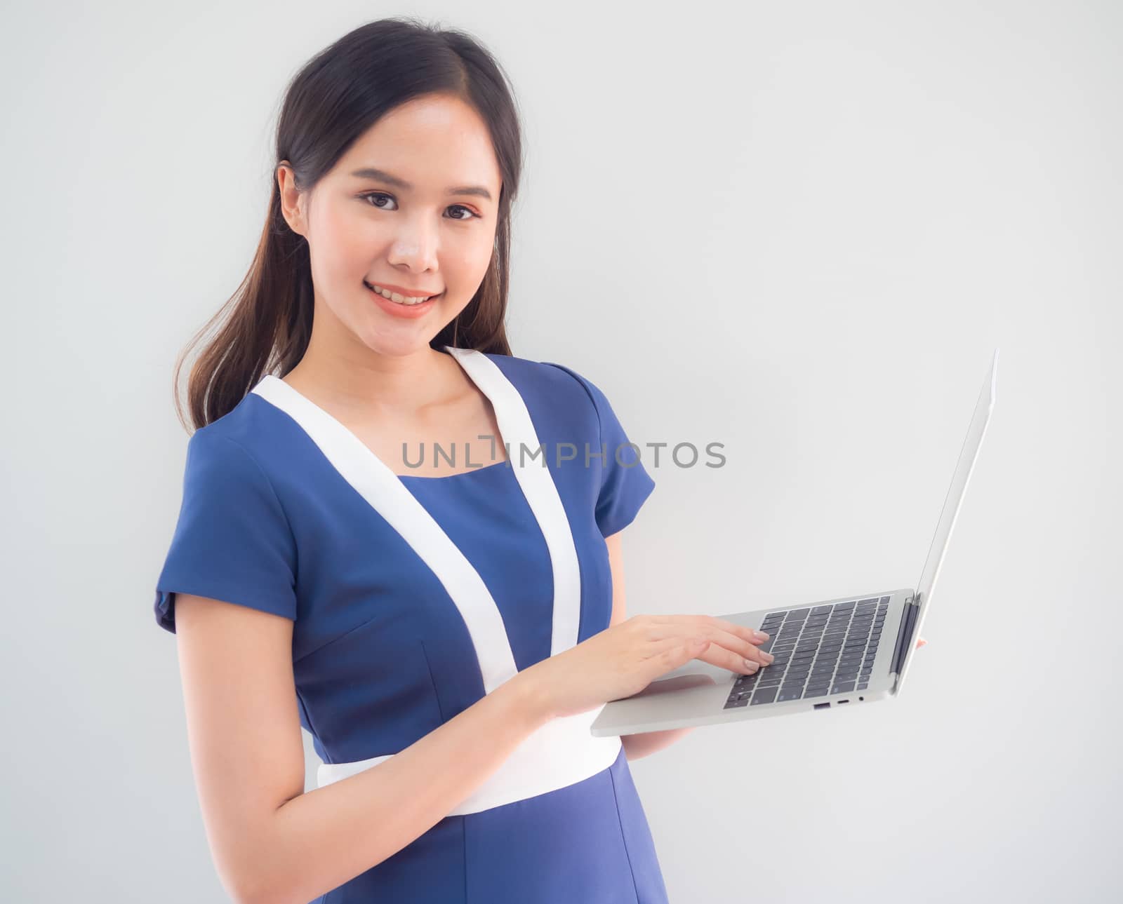 Portrait of a cute Asian businesswoman in a blue dress standing by panyajampatong