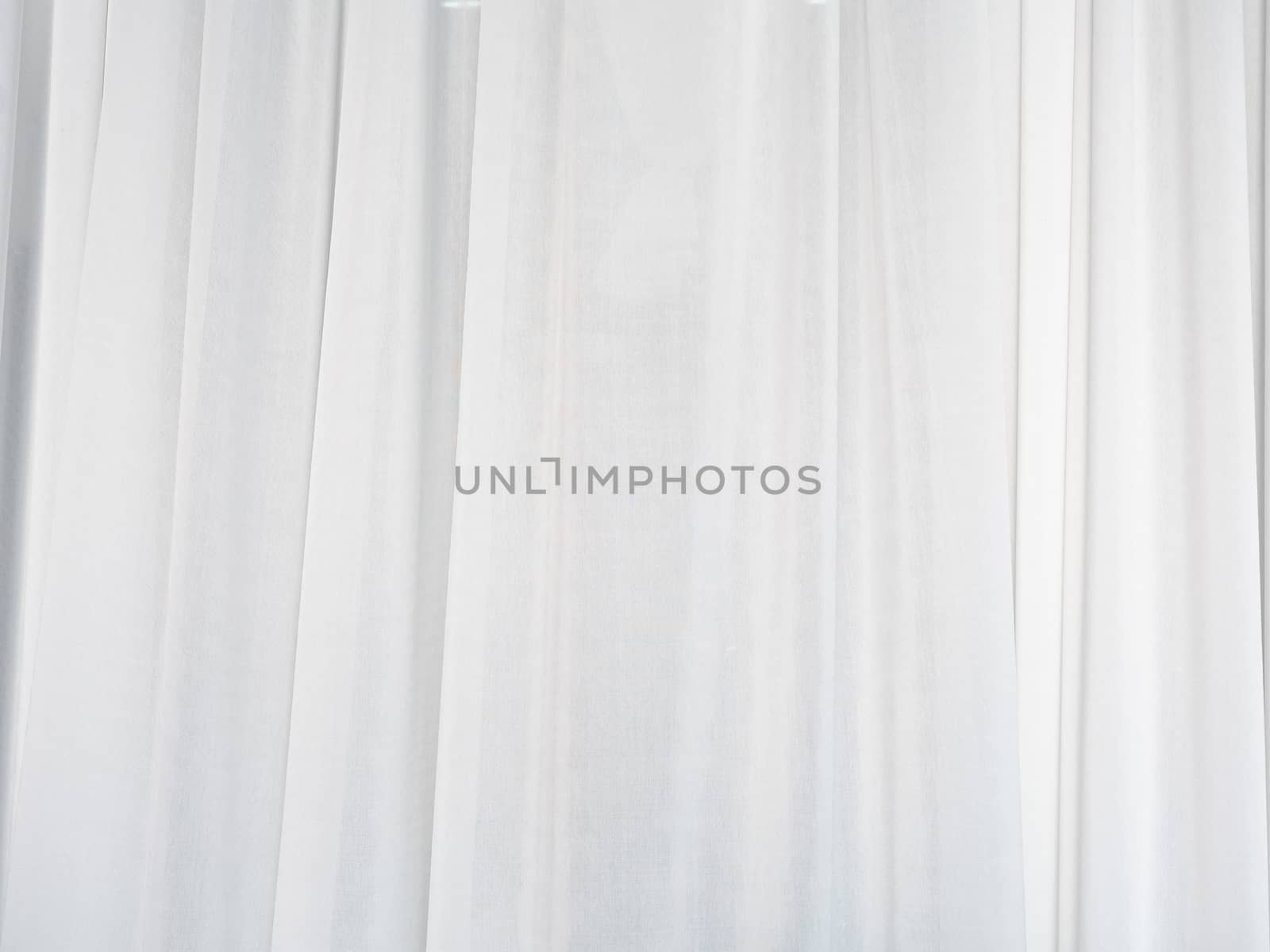 The white curtain is made of muslin fabric with soft sunlight in the morning passing through.