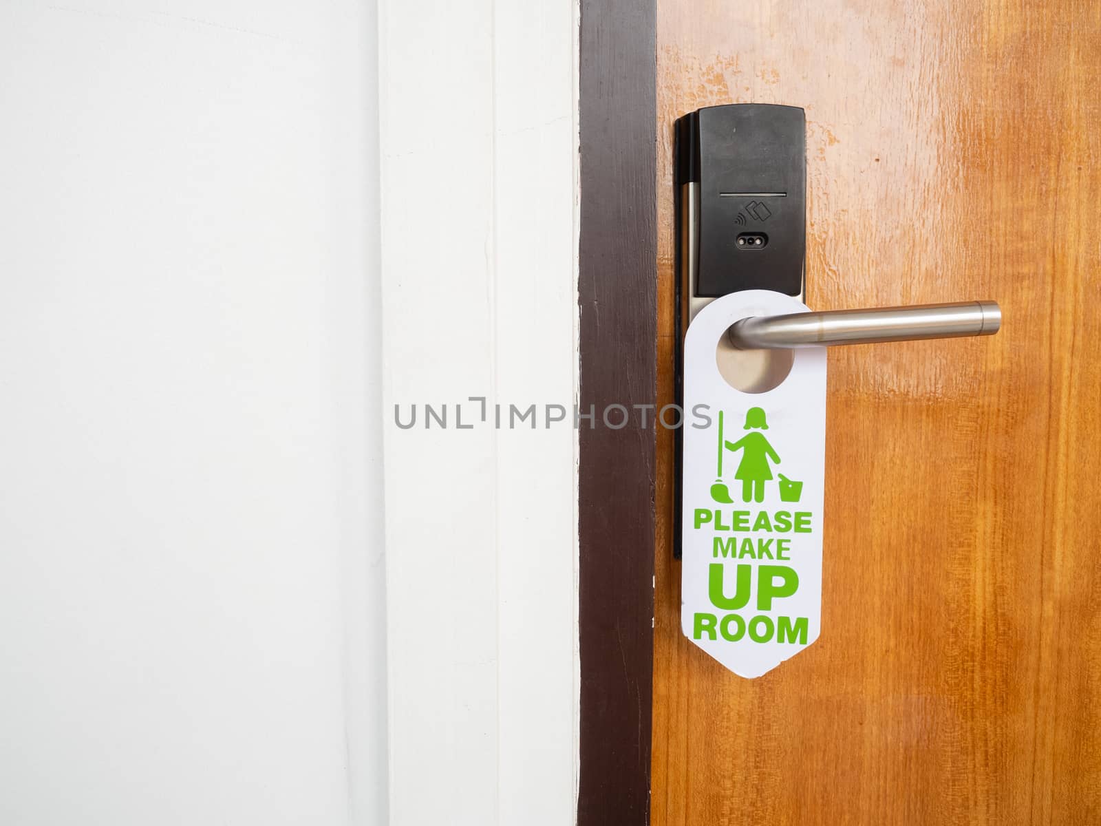 Make up room sign attached to the front of the room that is closed inside the hotel on the wooden door with stainless steel handles and use the electronic key system.
