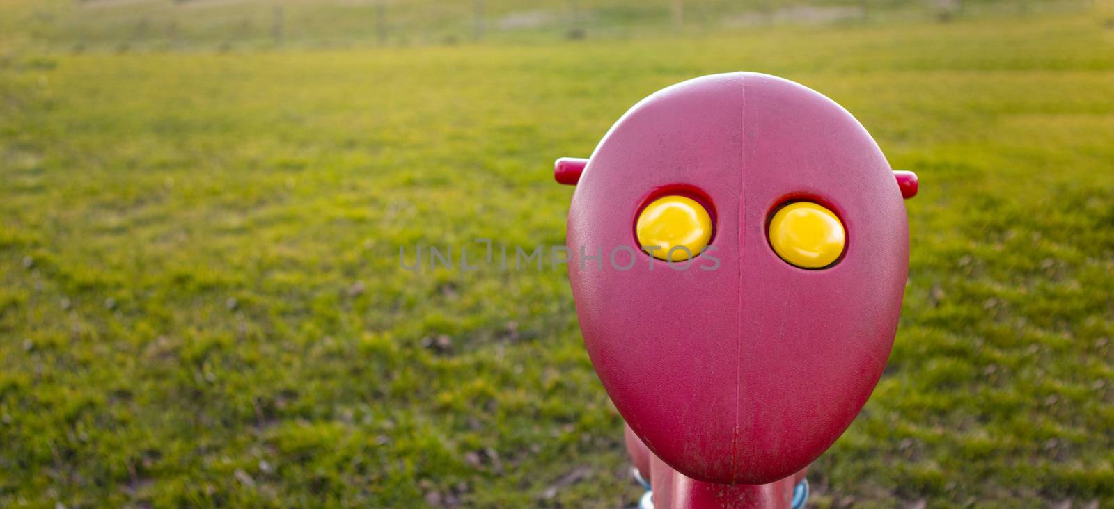 funny kids toy with a face and yellow eyes out in green grass