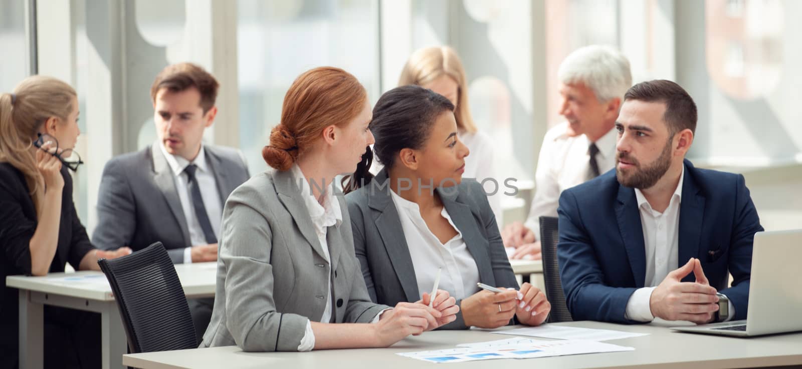 Business team sitting by the table with laptop and documents in office