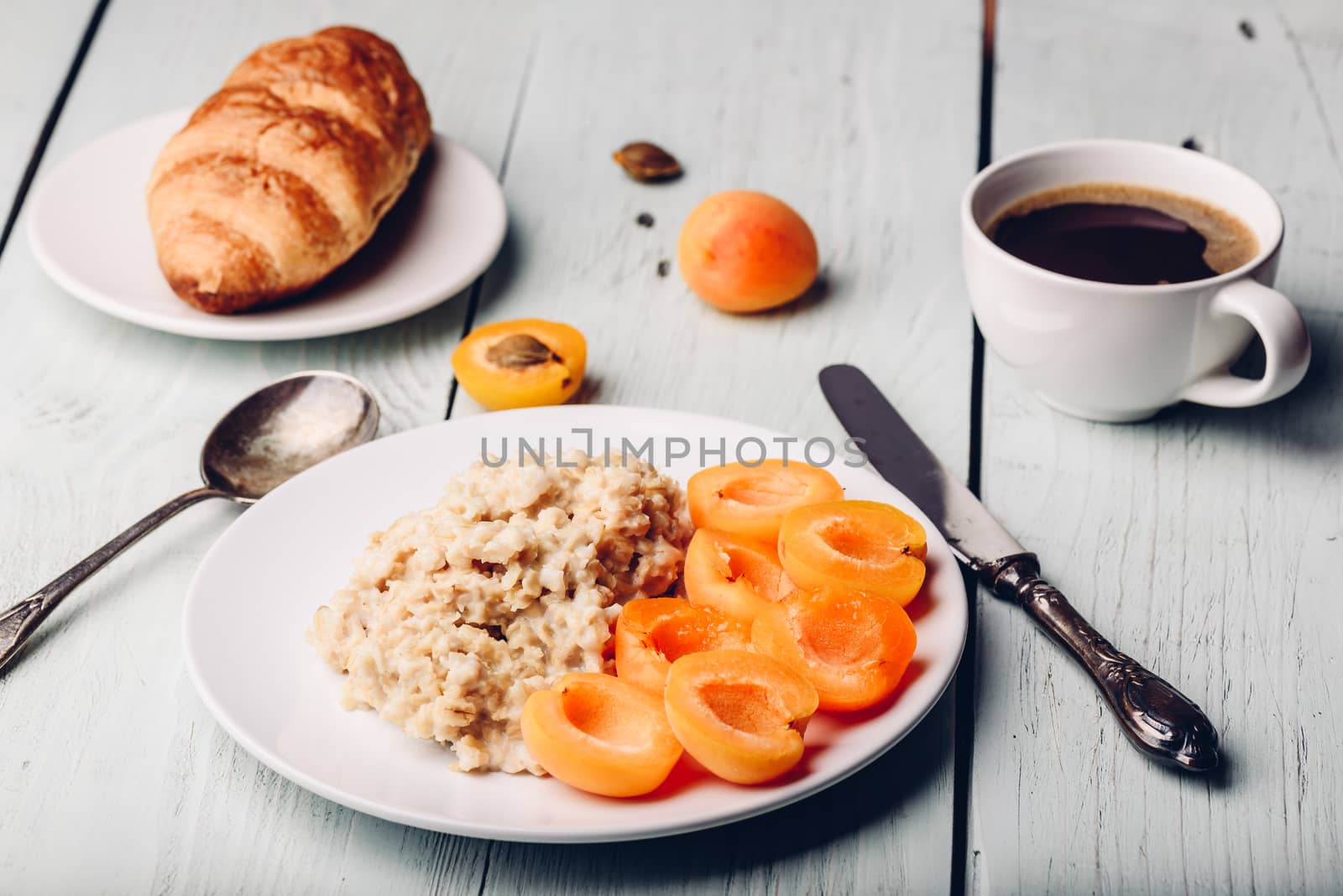 Breakfast set. Porridge with sliced apricot, cup of coffee, glass of grapefruit juice and croissant