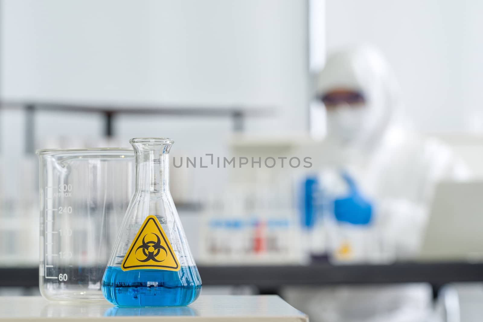 Erlenmeyer Flask contains blue liquid chemicals on a white laboratory table.