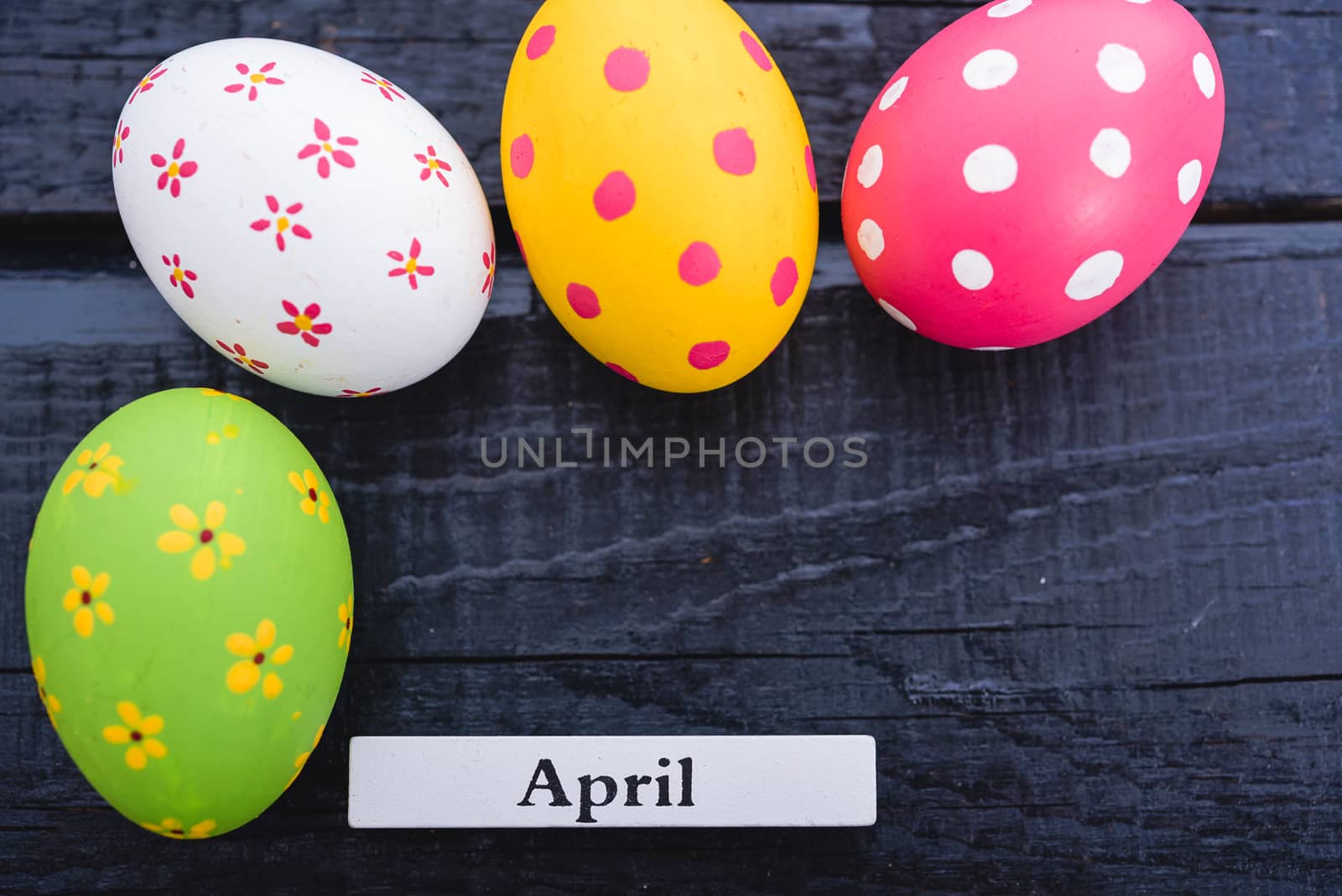 Easter eggs top view on black wooden background have April lable and copy space for use