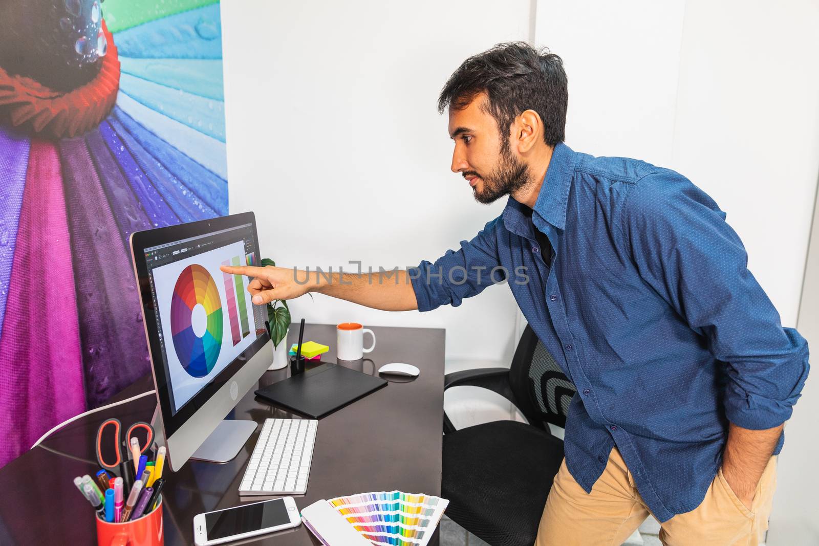 Young bearded man pointing at computer. Business employee working serious and concentrated.