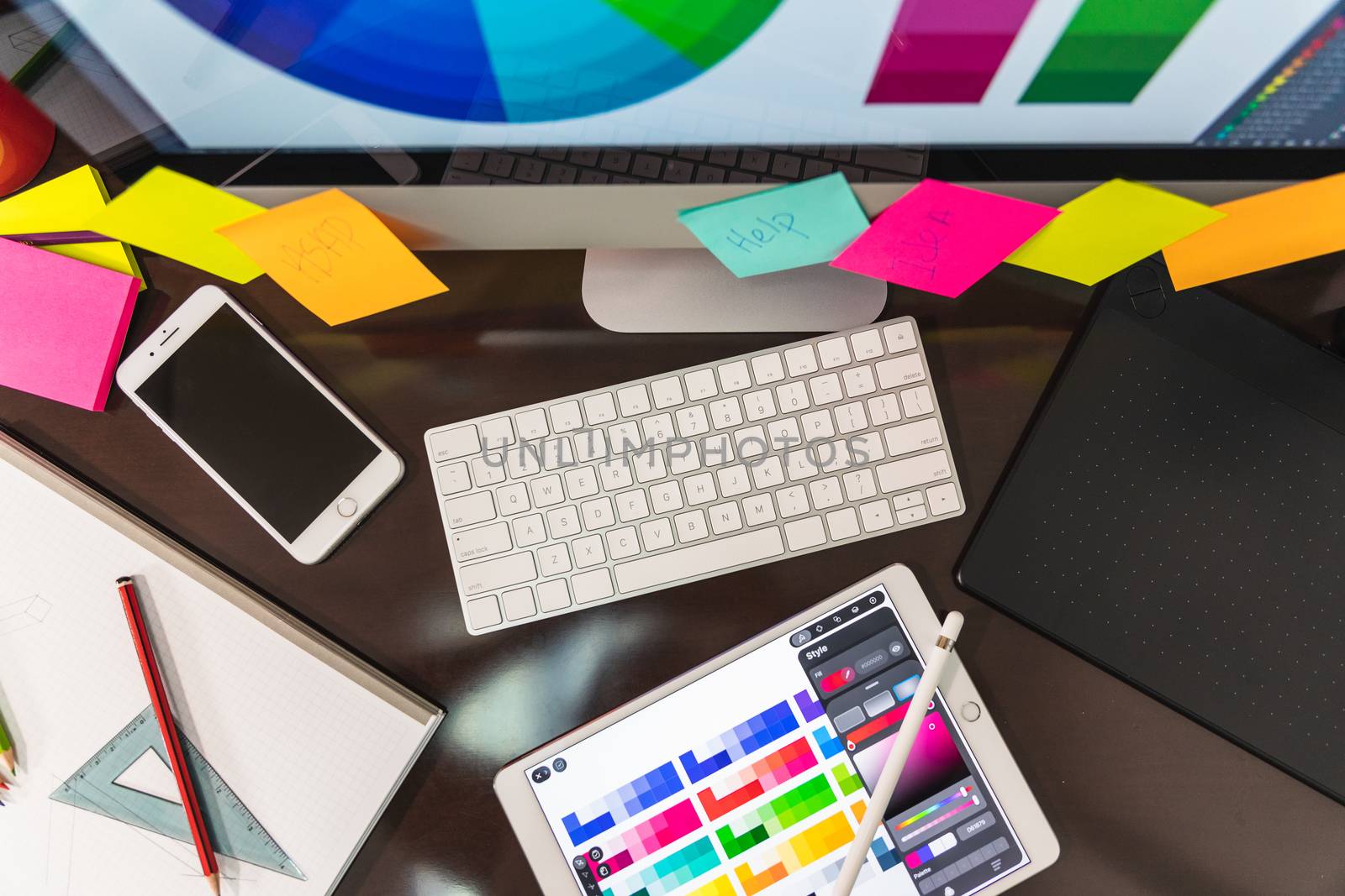 Top View of a graphic designer at work. Color swatch samples over wooden table