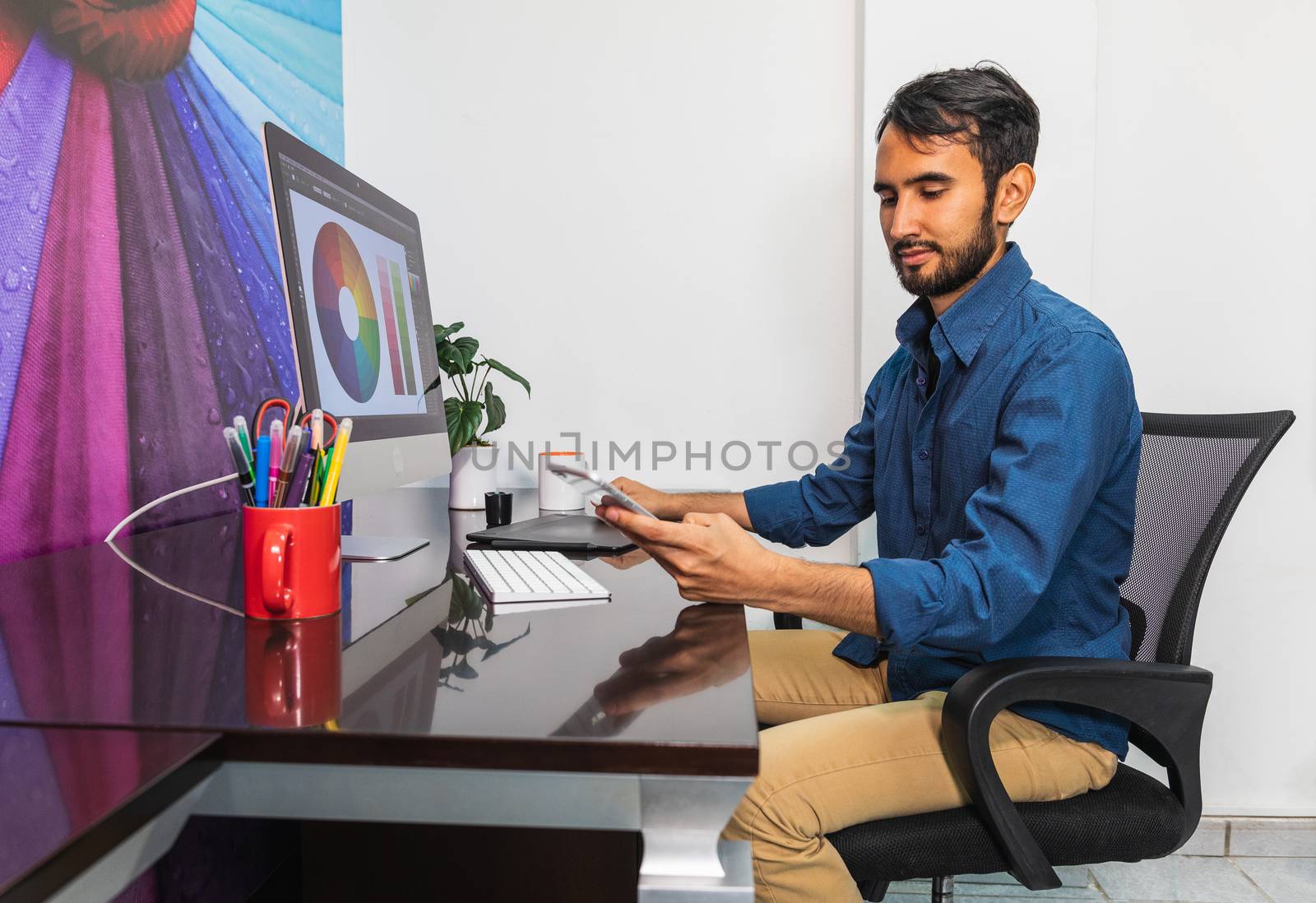 Side view. Young bearded businessman sitting in office by bmphotographypty