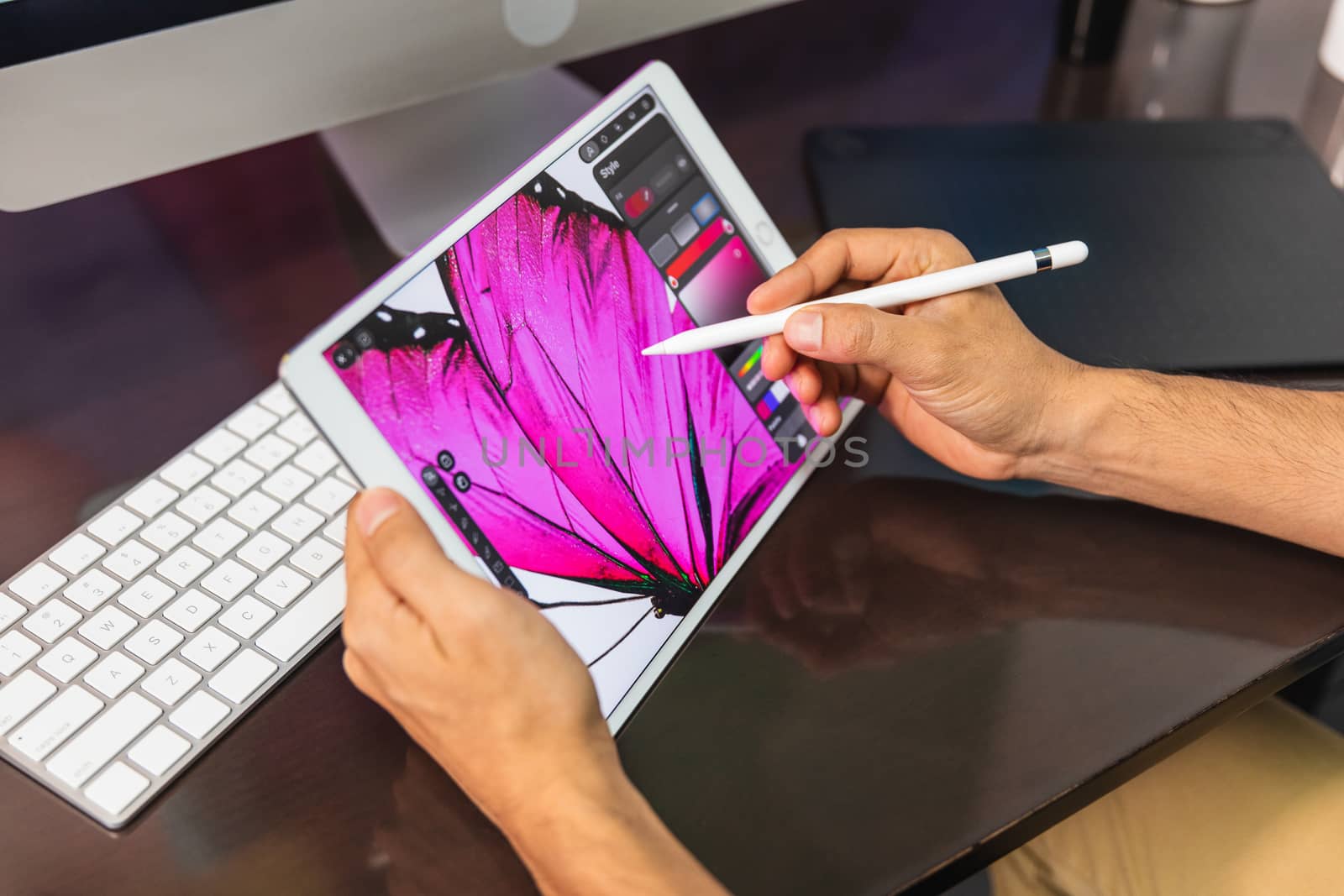 Close Up view. Man sitting in office at table and is using a tablet. Man Drawing