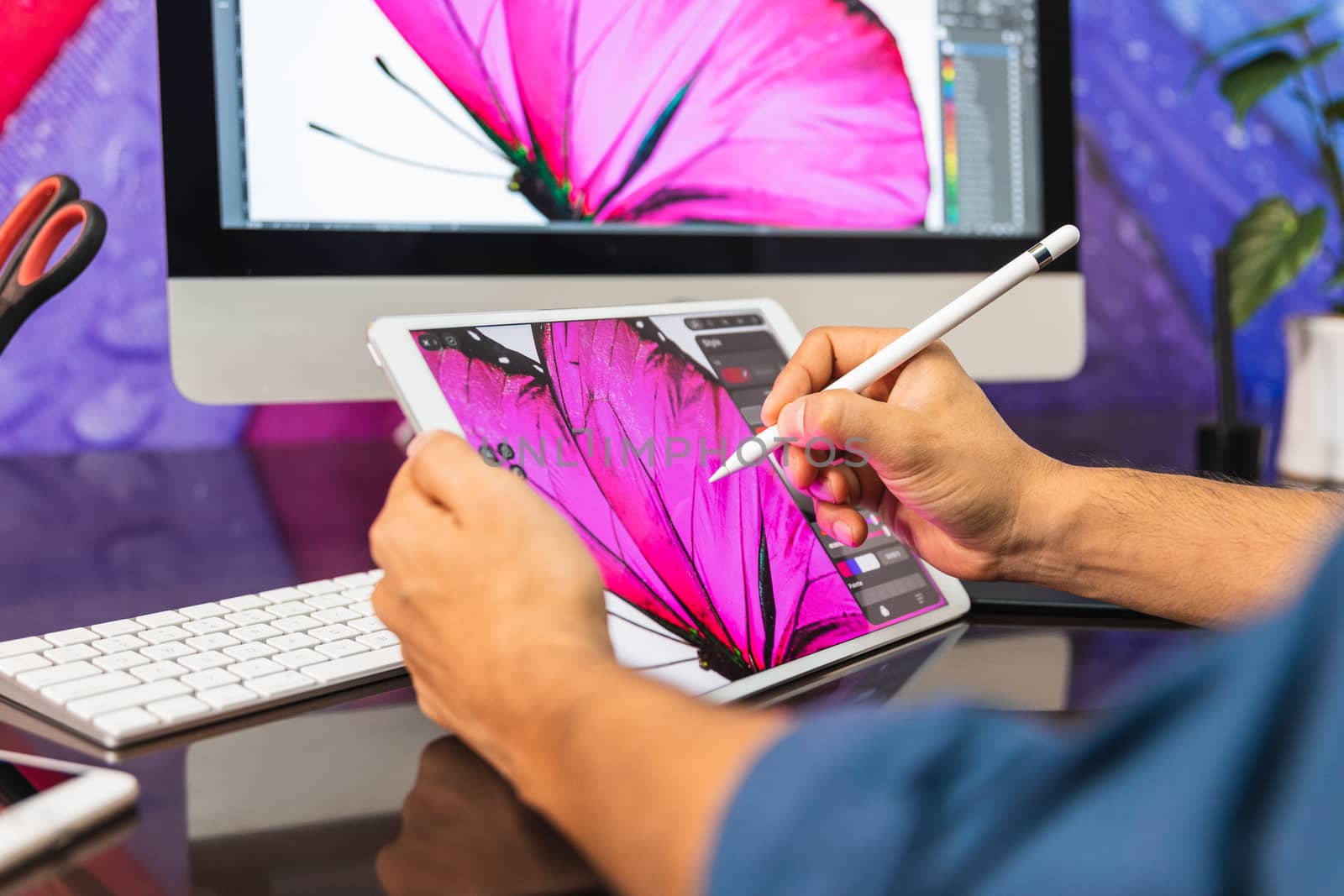 Close Up view. Man sitting in office at table and is using a tablet. Man Drawing