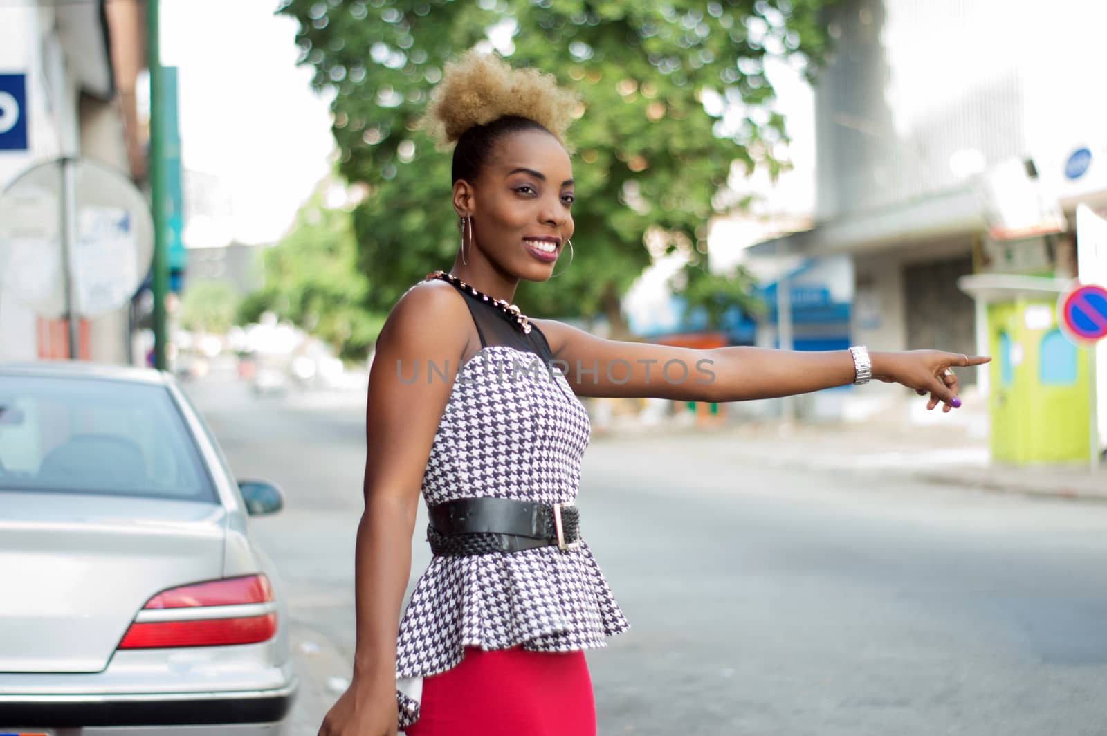 Pretty woman standing by the roadside, stopping a car with a sign