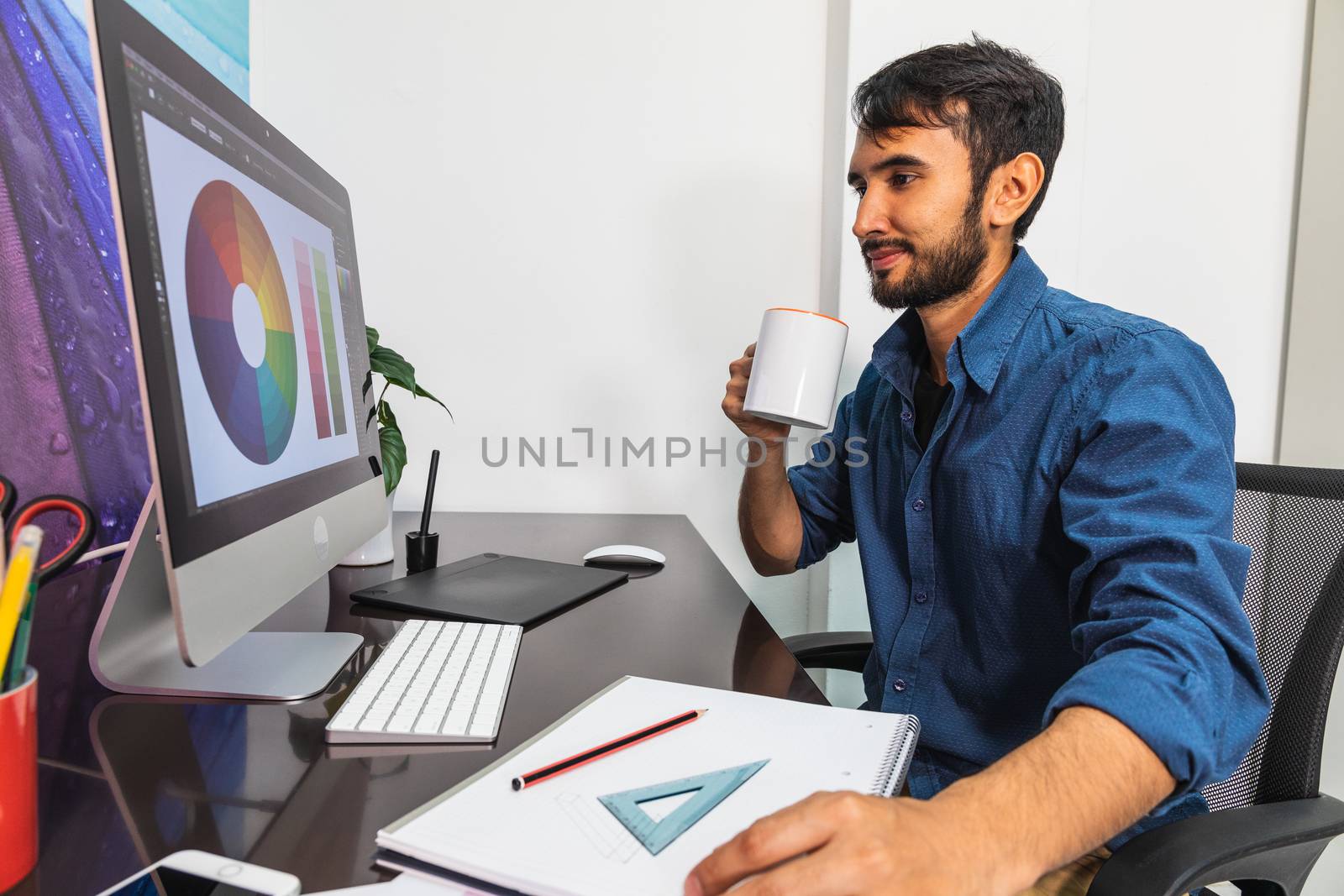 Side view. Young bearded businessman sitting in office by bmphotographypty