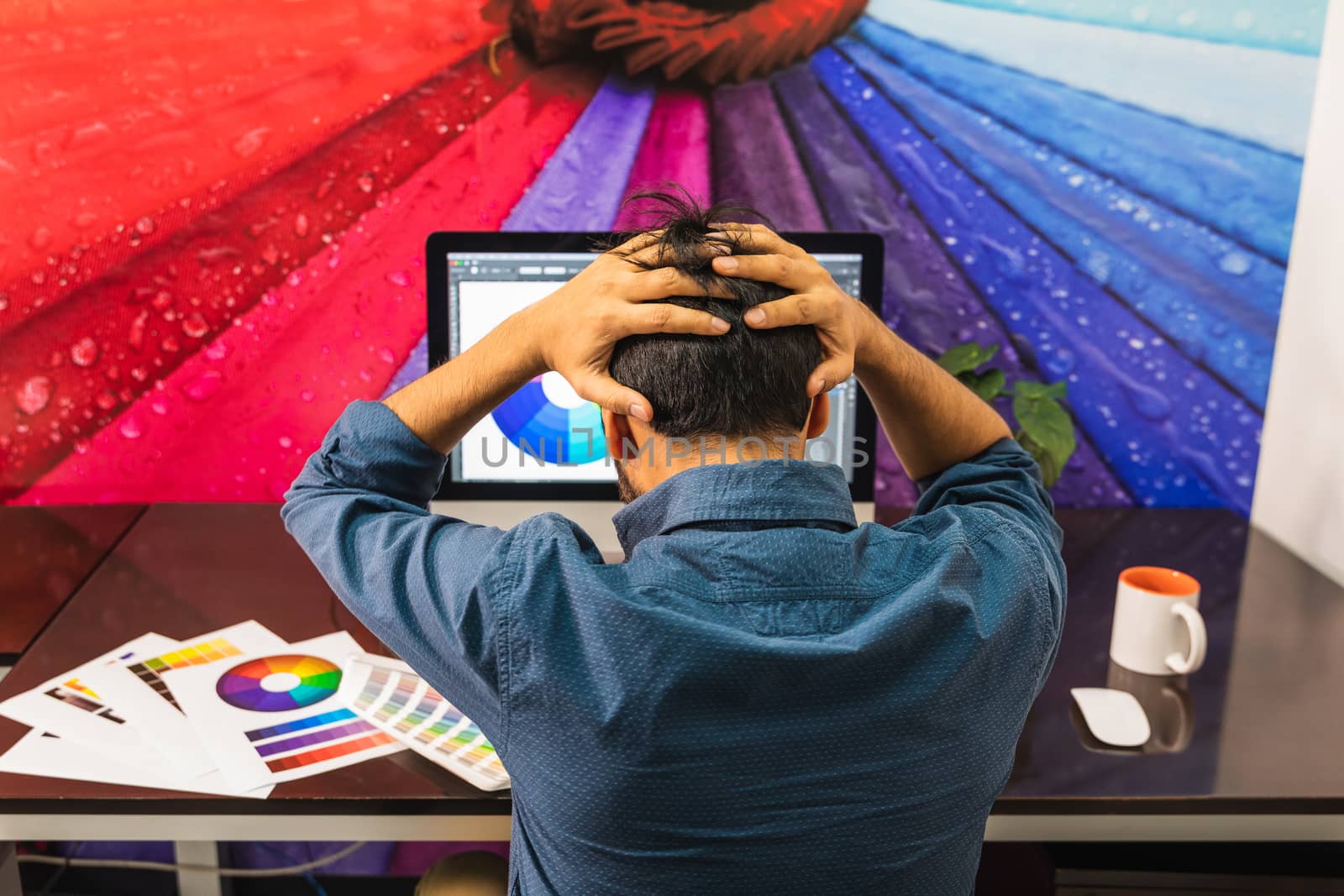 Male looking at his computer with hands on head showing frustrated angry emotion.