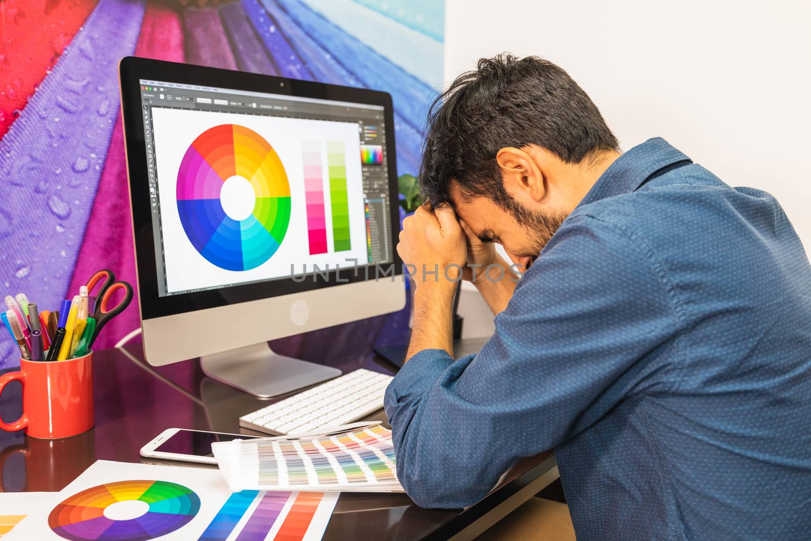 Side view of stressed, man sitting at the desk in office looking at computer