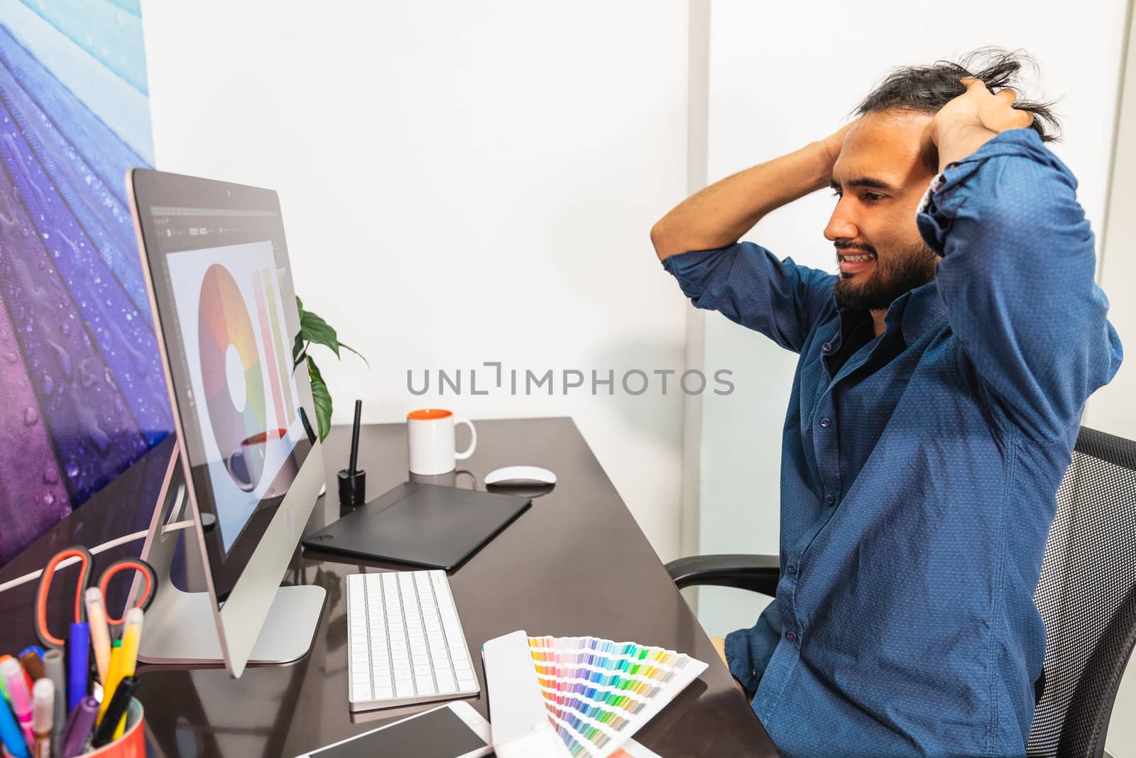 Male looking at his computer with hands on head showing frustrated angry emotion.