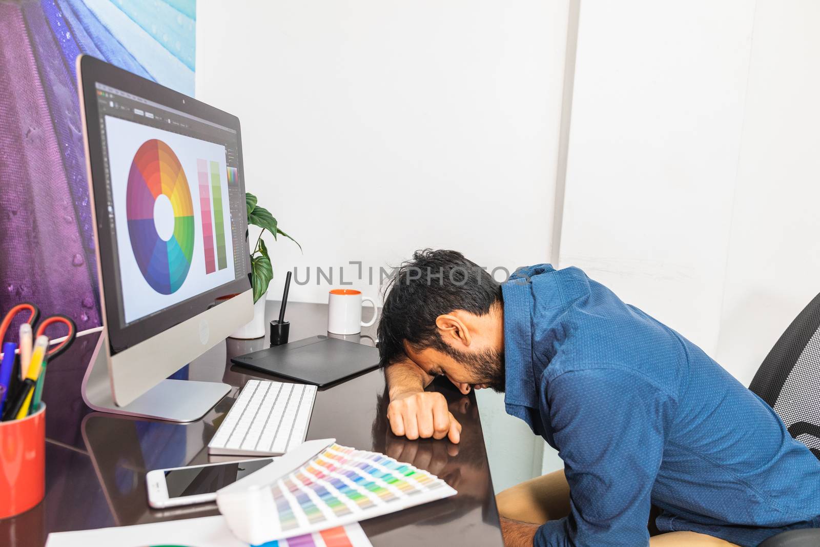 Sleeping young man working on computer. by bmphotographypty