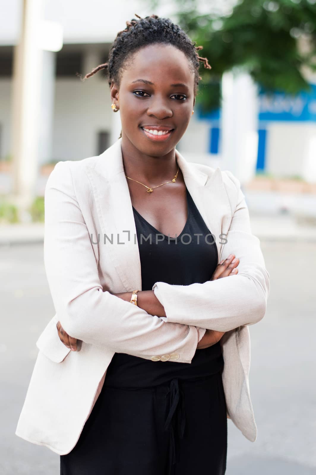Portrait of beautiful smiling businesswoman standing with arms crossed outdoors.