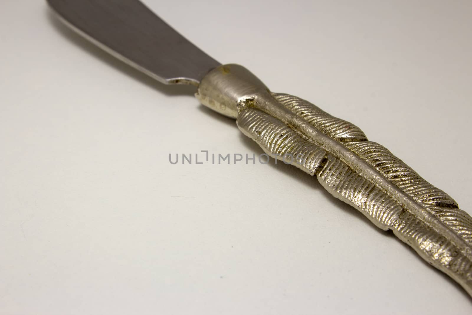 Butter knife with a handle shaped like a metal feather