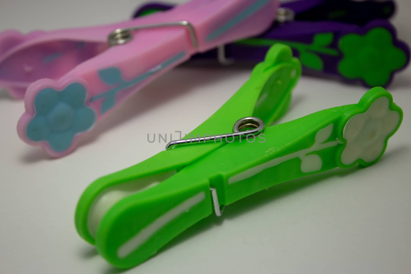 Closeup on a green plastic clothespin with others on the background