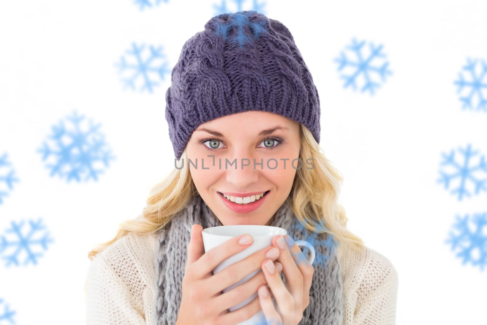 Pretty blonde in winter fashion holding mug against snowflakes