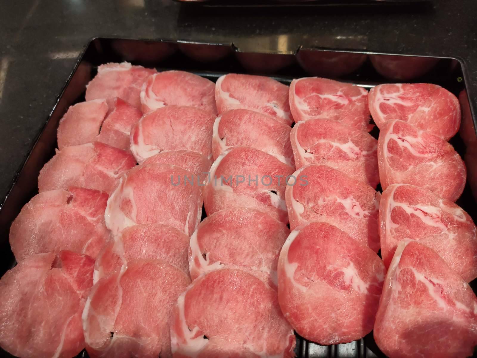 Fresh pork sliced for japanese hot pot on black plate by peerapixs