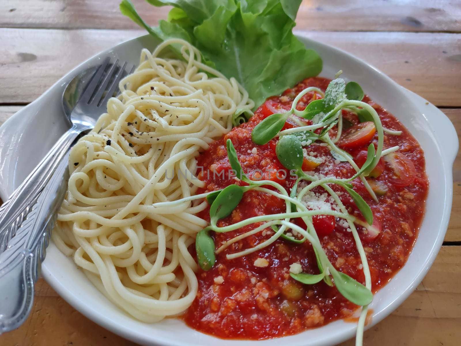 Tasty appetizing classic italian spaghetti pasta with tomato sauce, cheese parmesan and basil on plate by peerapixs