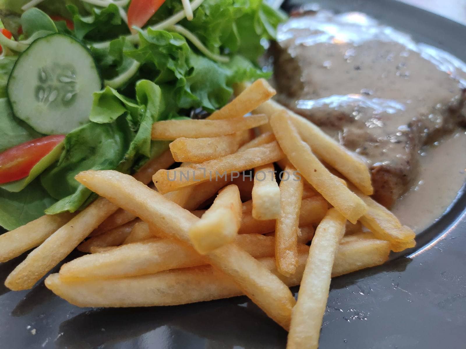The Selected focus on french fried with Steak ,salad on black disk