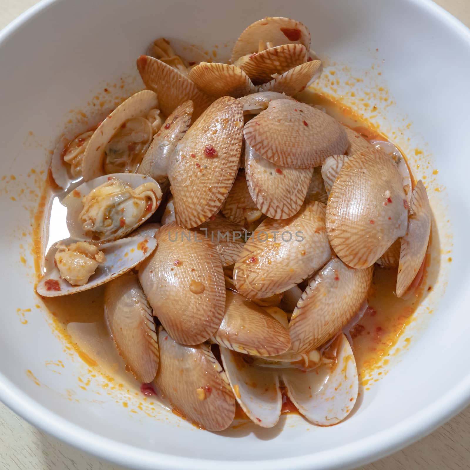 The close up of Thai Stir Fried Clams with Roasted Chili Paste on white bowl.