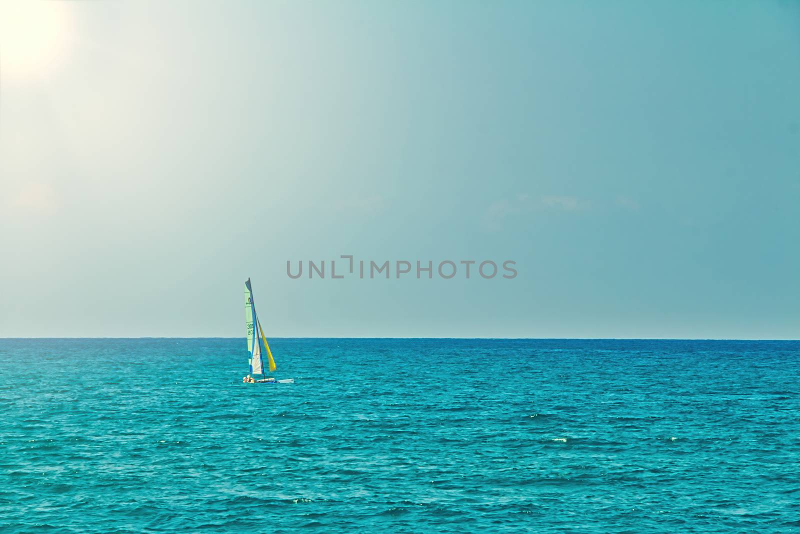 Small personal sailboat sailing in the open flat sea on a summer day. Calm seascape with blue sky. Sunny day in the mediterranean sea at Tel Aviv city. Copy Space view.