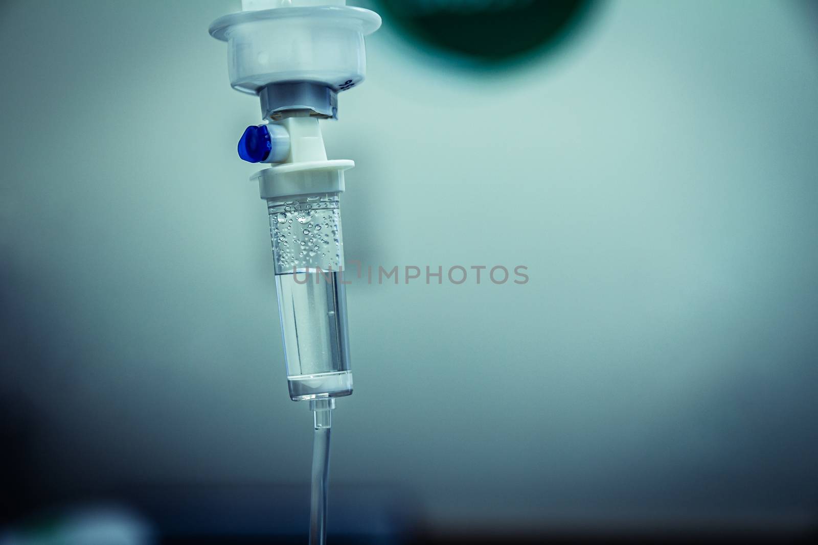 Set IV fluid intravenous drop saline drip in a hospital room. Close up, dark blue light background, selective focus and copy space.