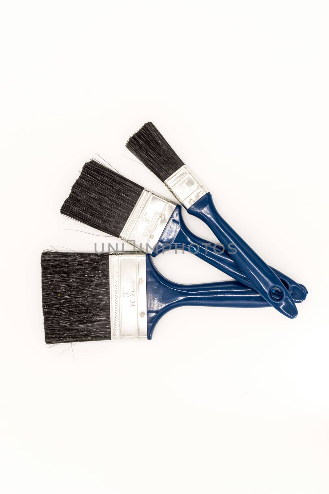 Three paint brushes with blue colored handles on an isolated white background