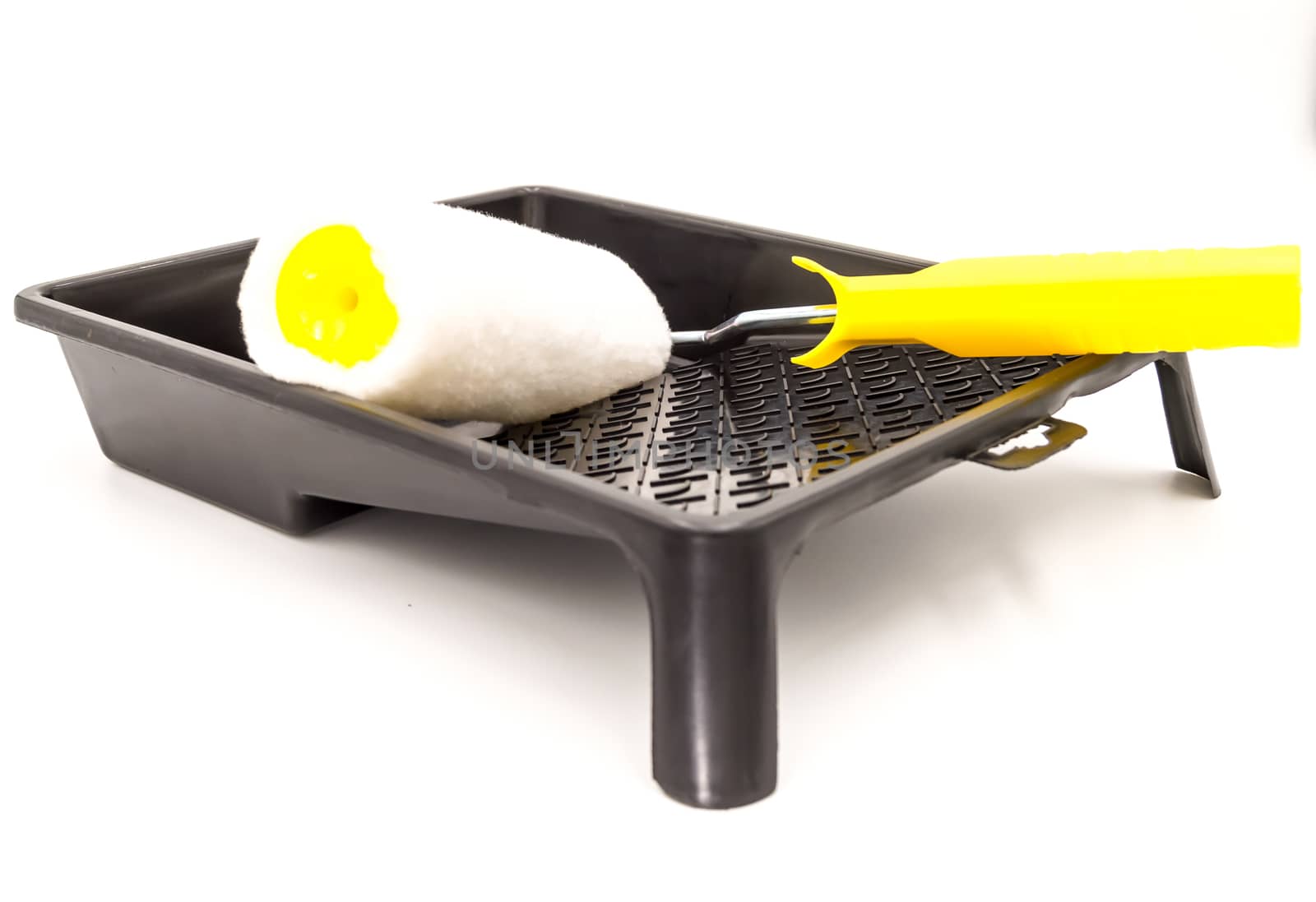 A clean paint roller rests on a black paint tray. Isolated on white background with clipping path.