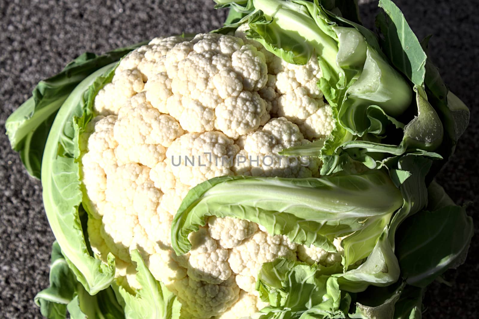 The picture shows fresh cauliflower with many leaves