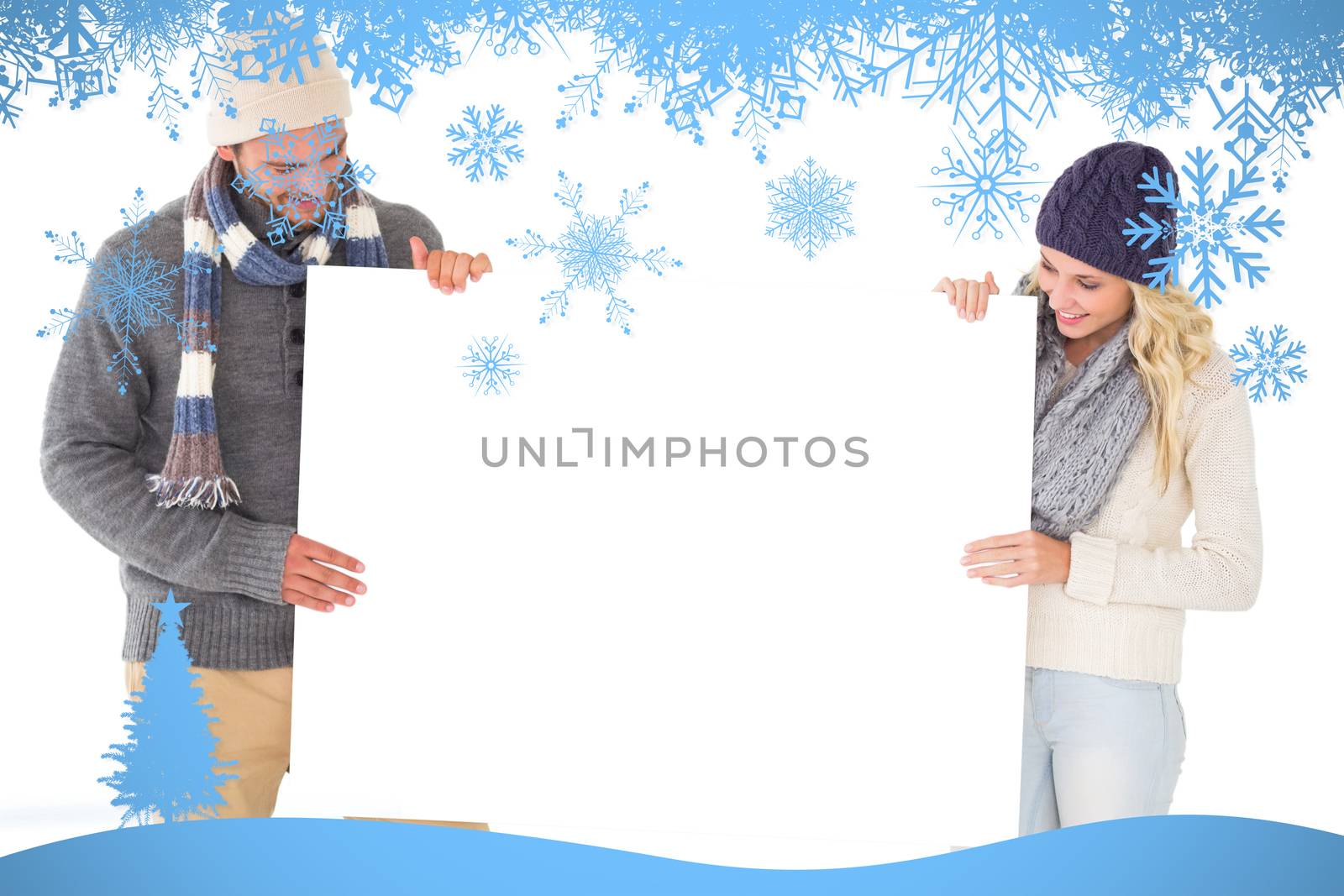 Attractive couple in winter fashion showing poster against snow flake frame in blue