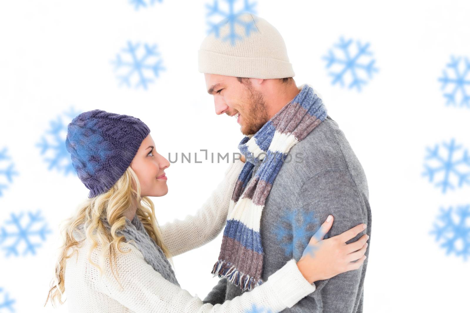 Attractive couple in winter fashion hugging against snowflakes