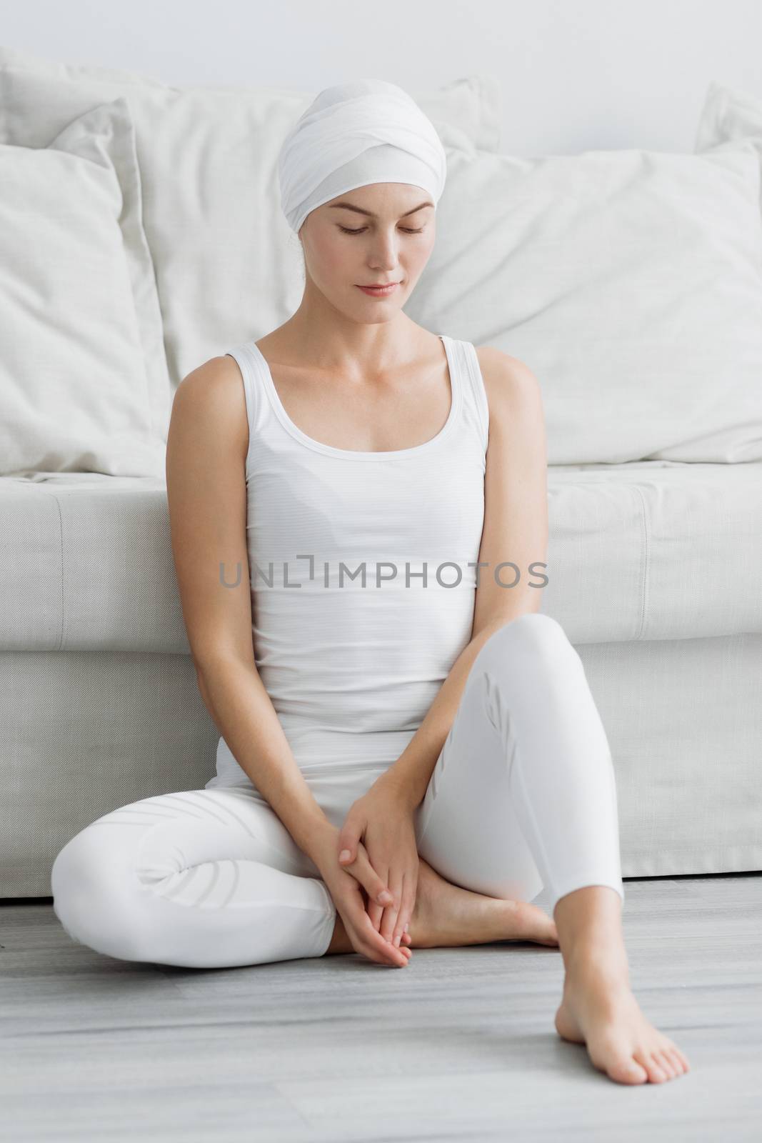 Pretty young woman in sportswear sitting on studio floor in difficult position while doing yoga
