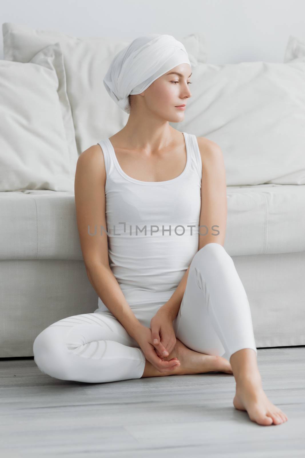 Pretty young woman in sportswear sitting on studio floor in difficult position while doing yoga