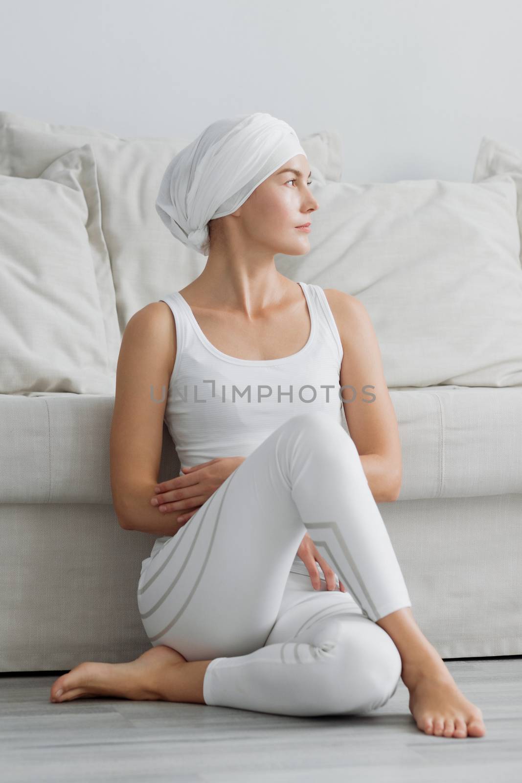 Pretty young woman in sportswear sitting on studio floor in difficult position while doing yoga