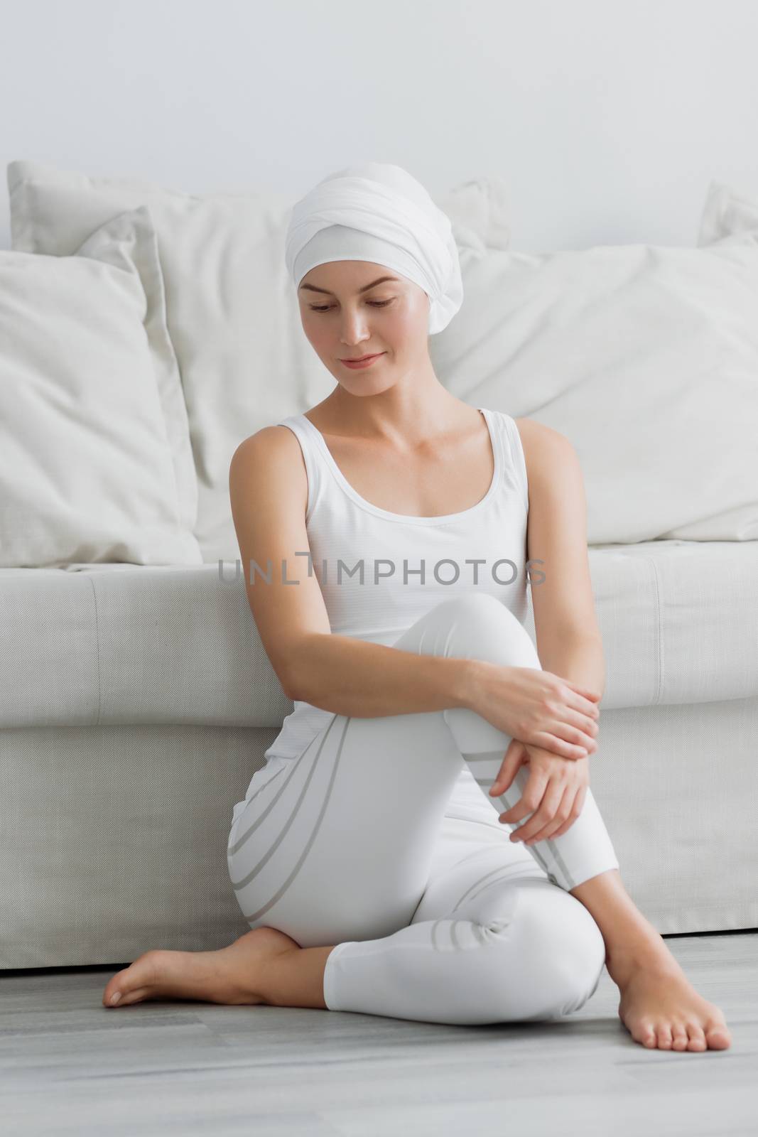 Pretty young woman in sportswear sitting on studio floor in difficult position while doing yoga